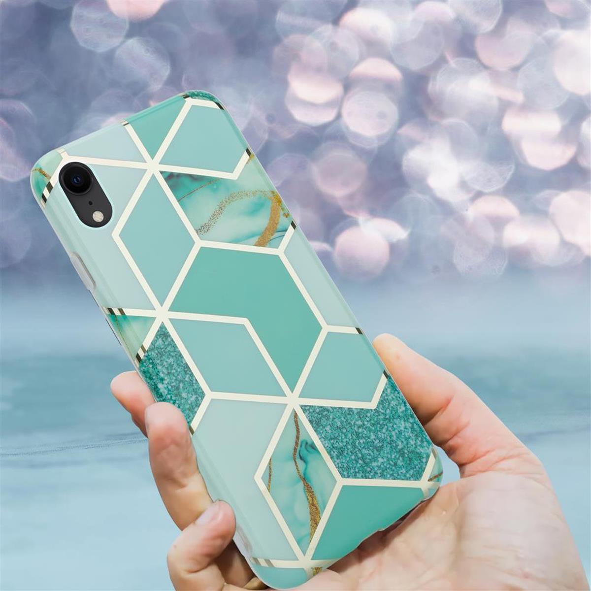 Custodia per telefono con motivo geometrico, blu, verde e oro. Tenuta in mano, che mostra il design posteriore.