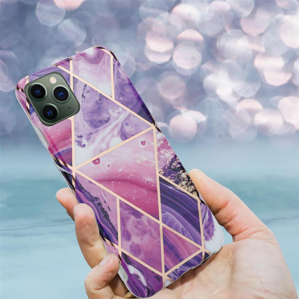 Mano che tiene una custodia per telefono con un design geometrico viola e oro.