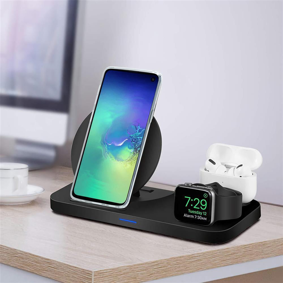 Stazione di ricarica wireless con telefono, auricolari e smartwatch. Gli oggetti sono su un tavolo.