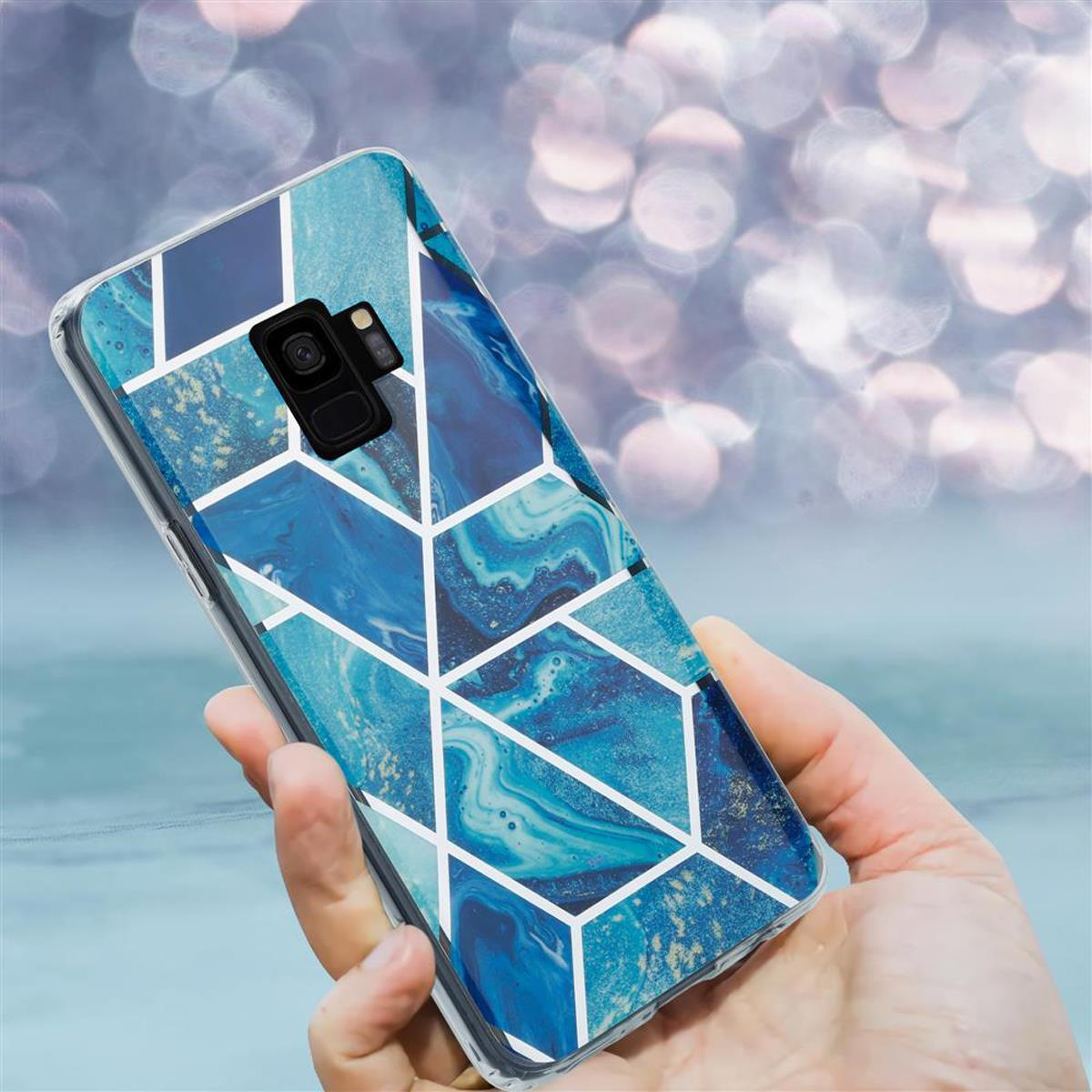 Custodia per telefono con design a marmo blu e linee geometriche bianche. Tenuta in mano.