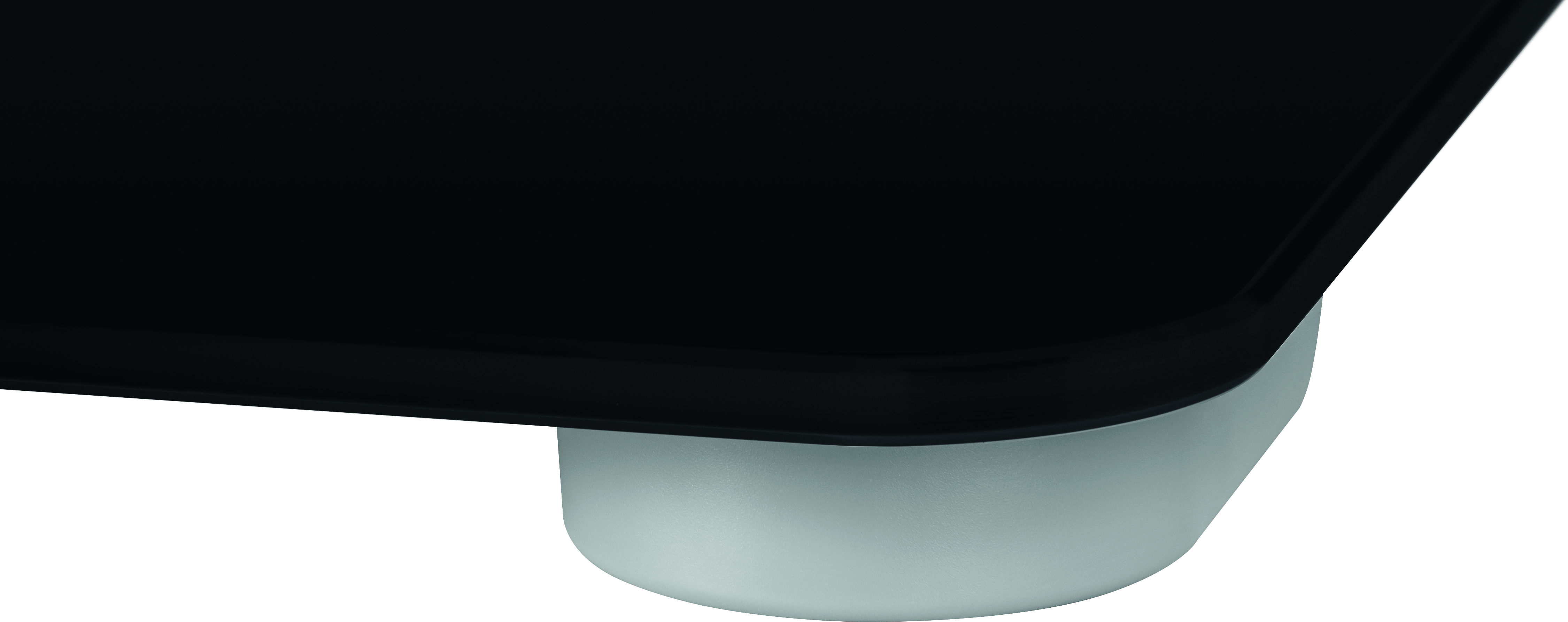 Czarny, błyszczący, prostokątny obiekt z zaokrąglonymi rogami. Widoczna jest biała podstawa.