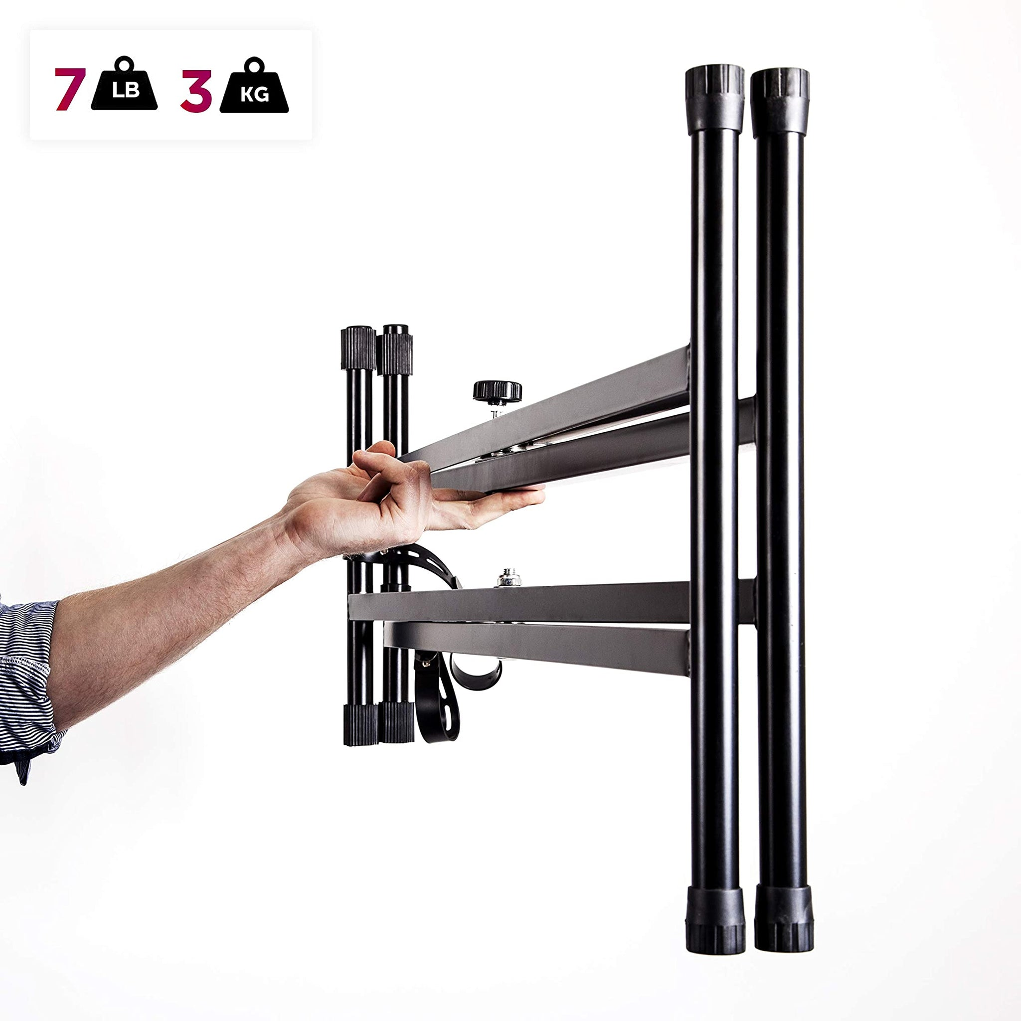 Una mano sujeta un soporte de TV negro y gris con una etiqueta de peso de 7 lb y 3 kg.