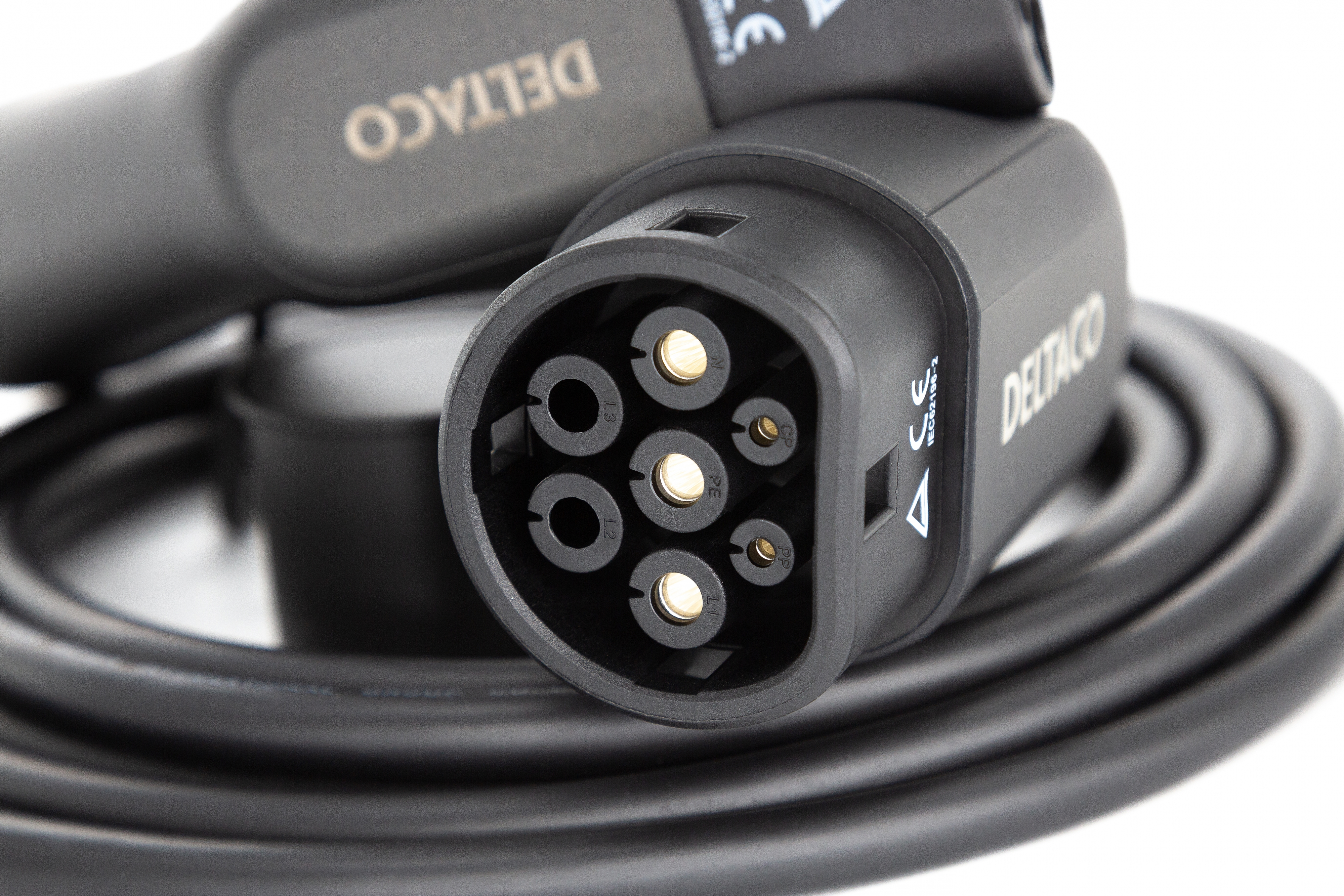 Close-up of an EV charger plug. Black, with multiple pin connectors, and a white background.