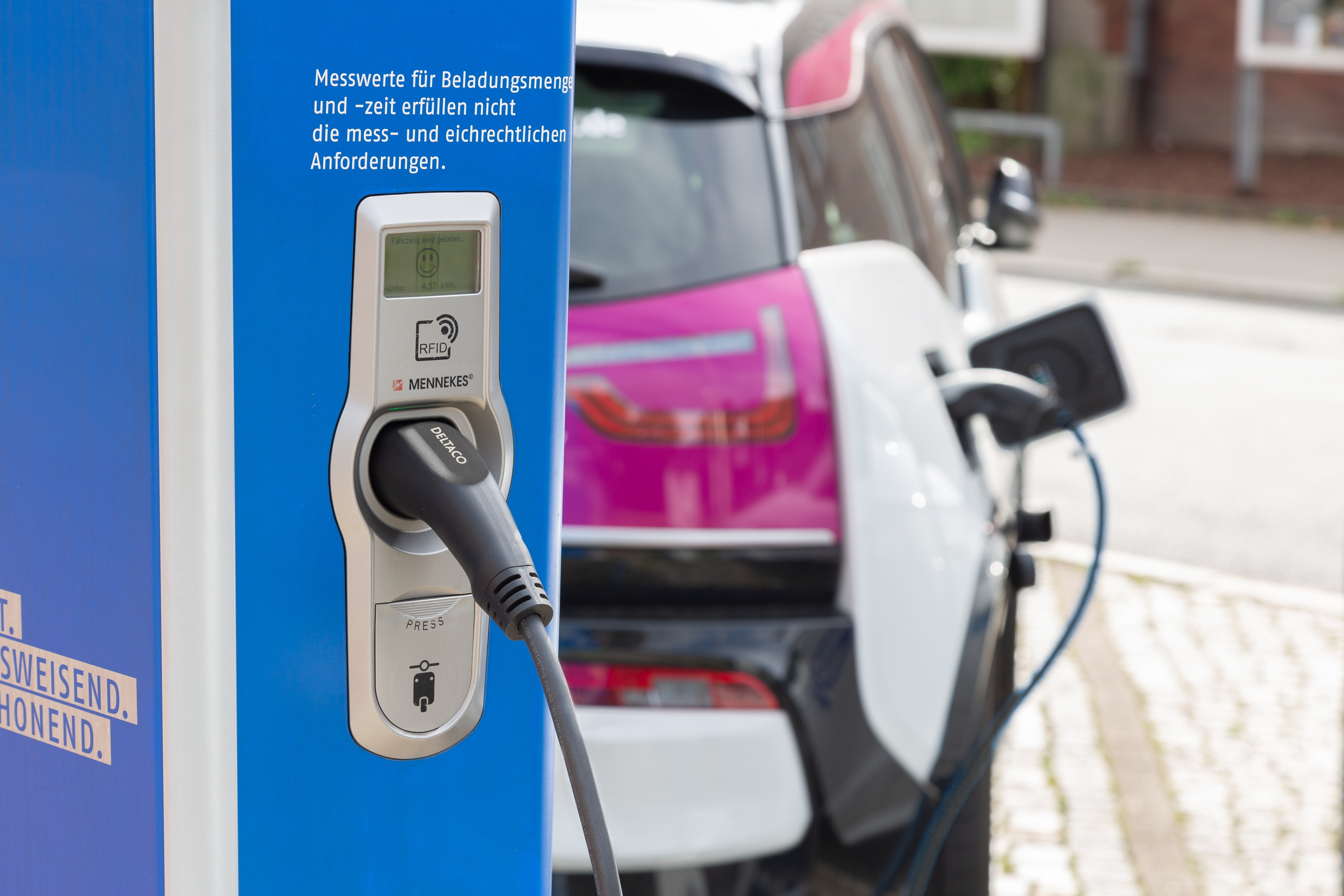 Elektroauto lädt an einer Station. Blaue und weiße Station, rosa und weißes Auto.