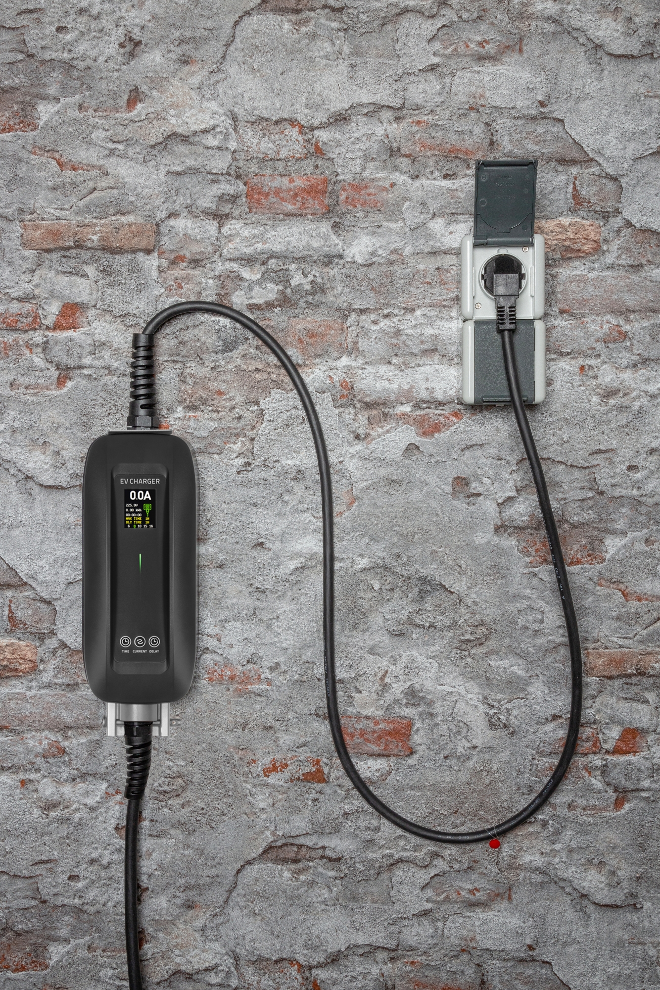 Ein EV-Ladegerät an einer Backsteinmauer. Ein schwarzes Ladegerät ist über ein schwarzes Kabel mit einer Steckdose verbunden.
