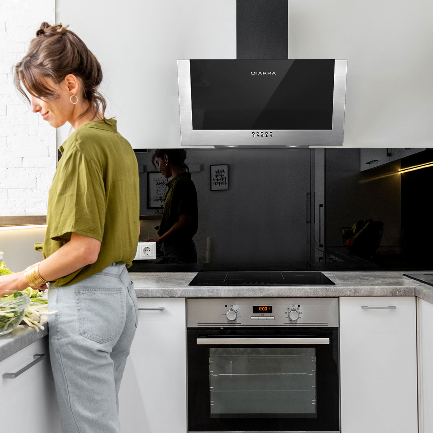 Vrouw in keuken die eten bereidt. Een CIARRA afzuigkap boven een kookplaat.