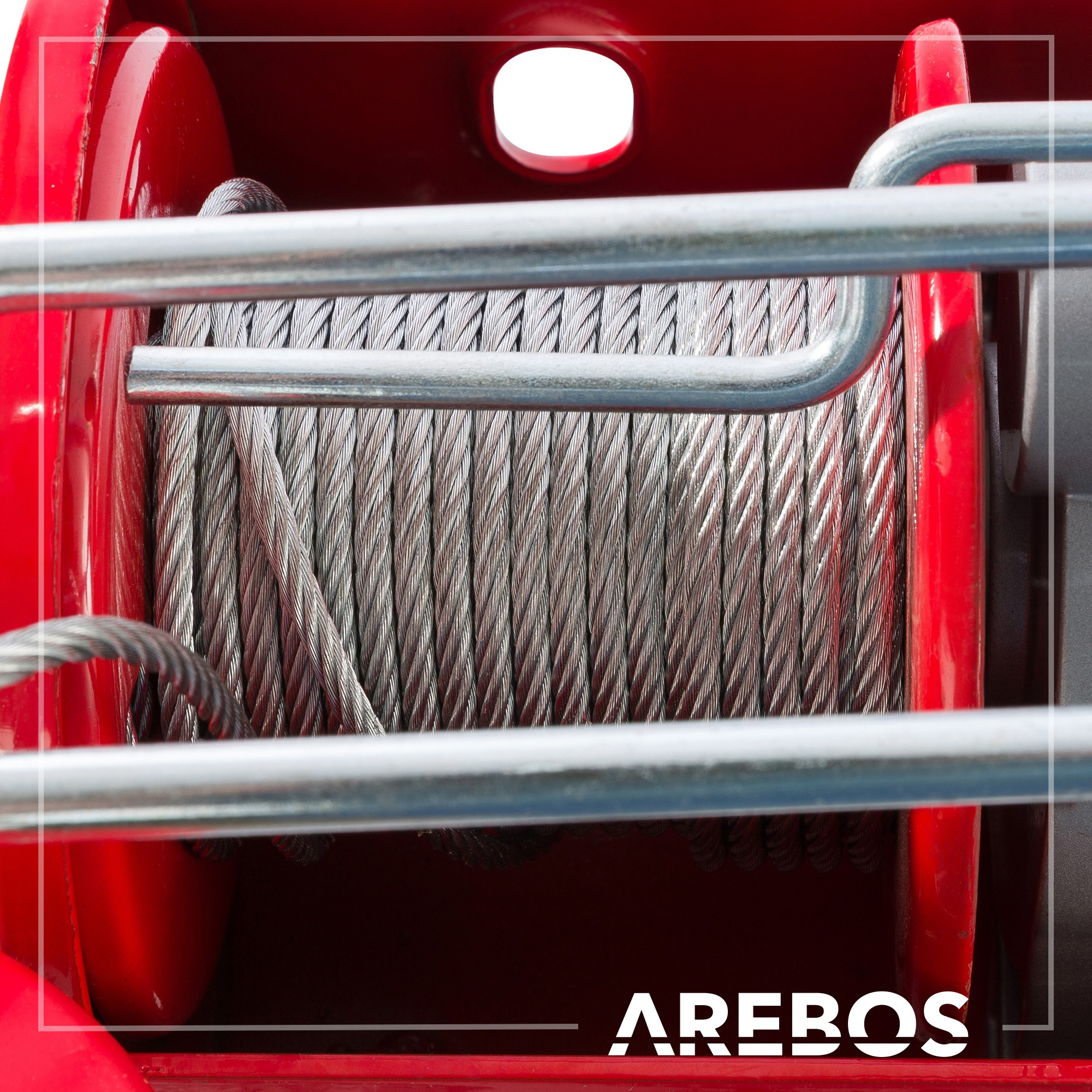 Rote mechanische Winde mit Stahlseil. Der Markenname AREBOS ist sichtbar.
