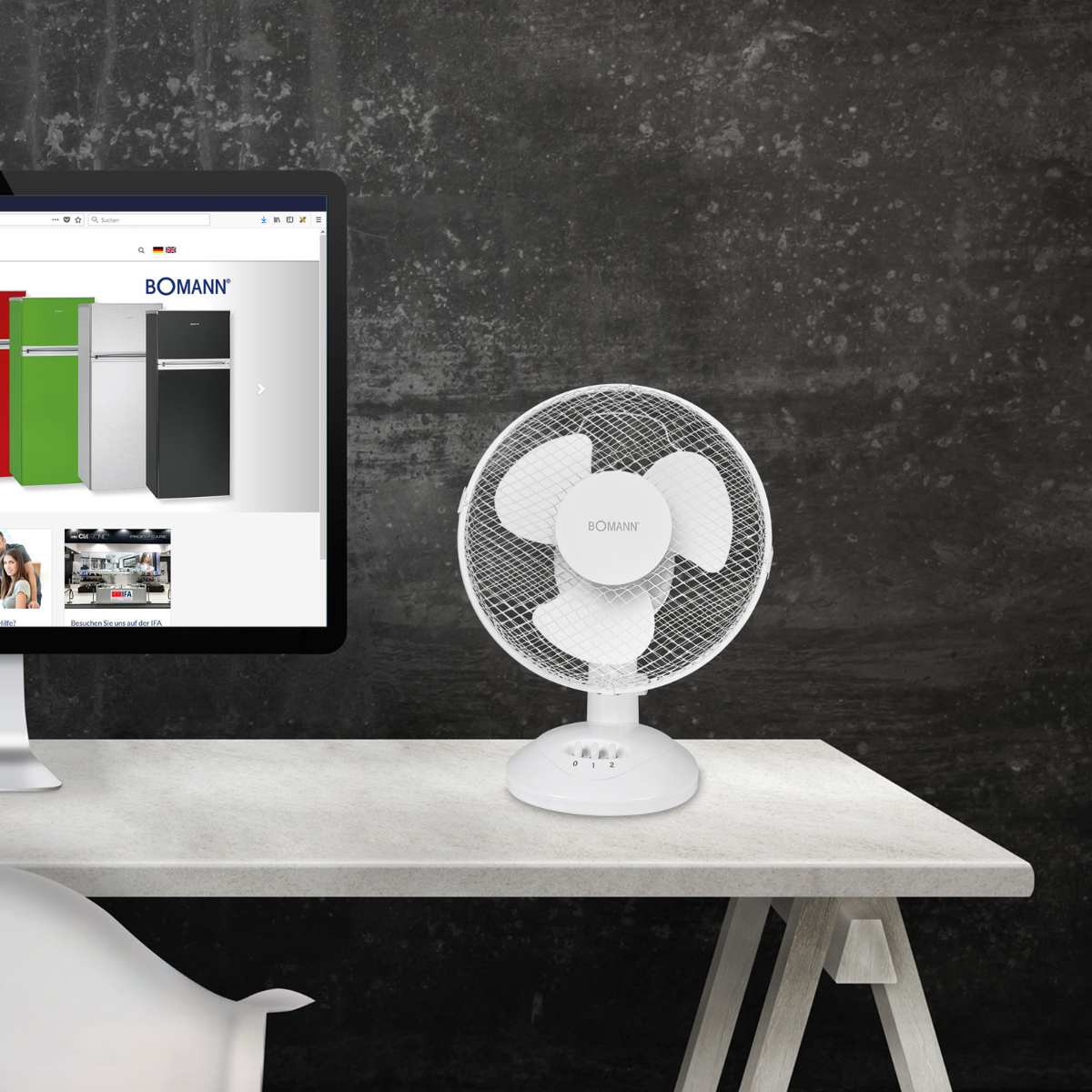 Biały wentylator na biurku z monitorem komputera.