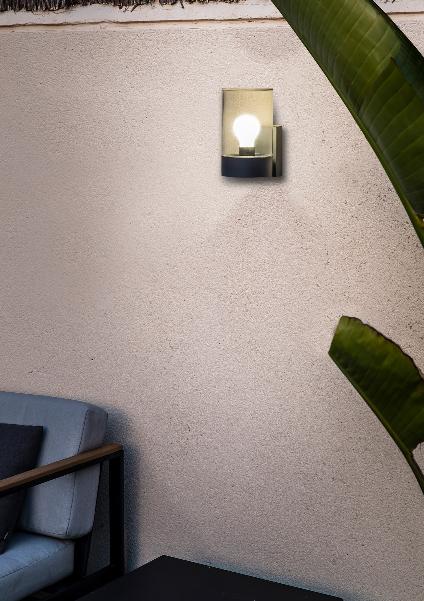 Lampada da esterno a parete. Corpo nero, copertura in vetro ed è accesa.