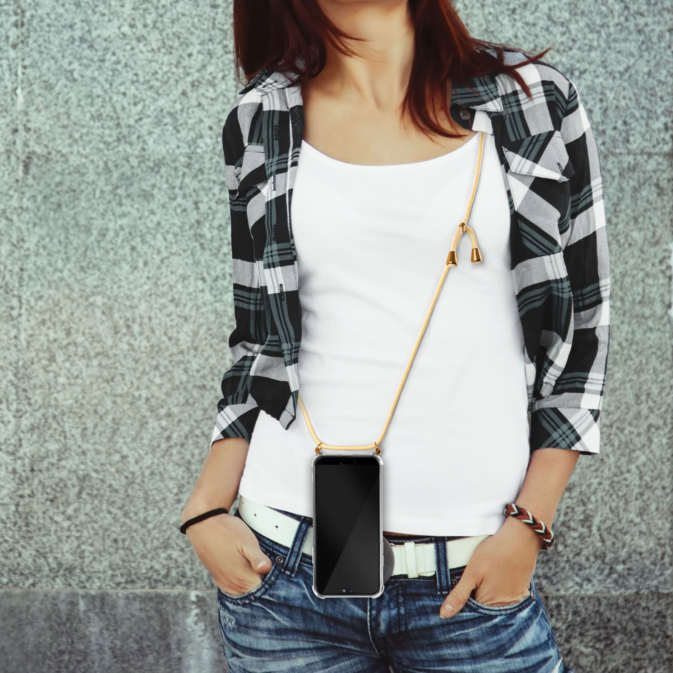 Frau mit einem Handy-Lanyard. Das Telefon ist schwarz. Sie trägt ein weißes Hemd, Jeans und ein kariertes Hemd.