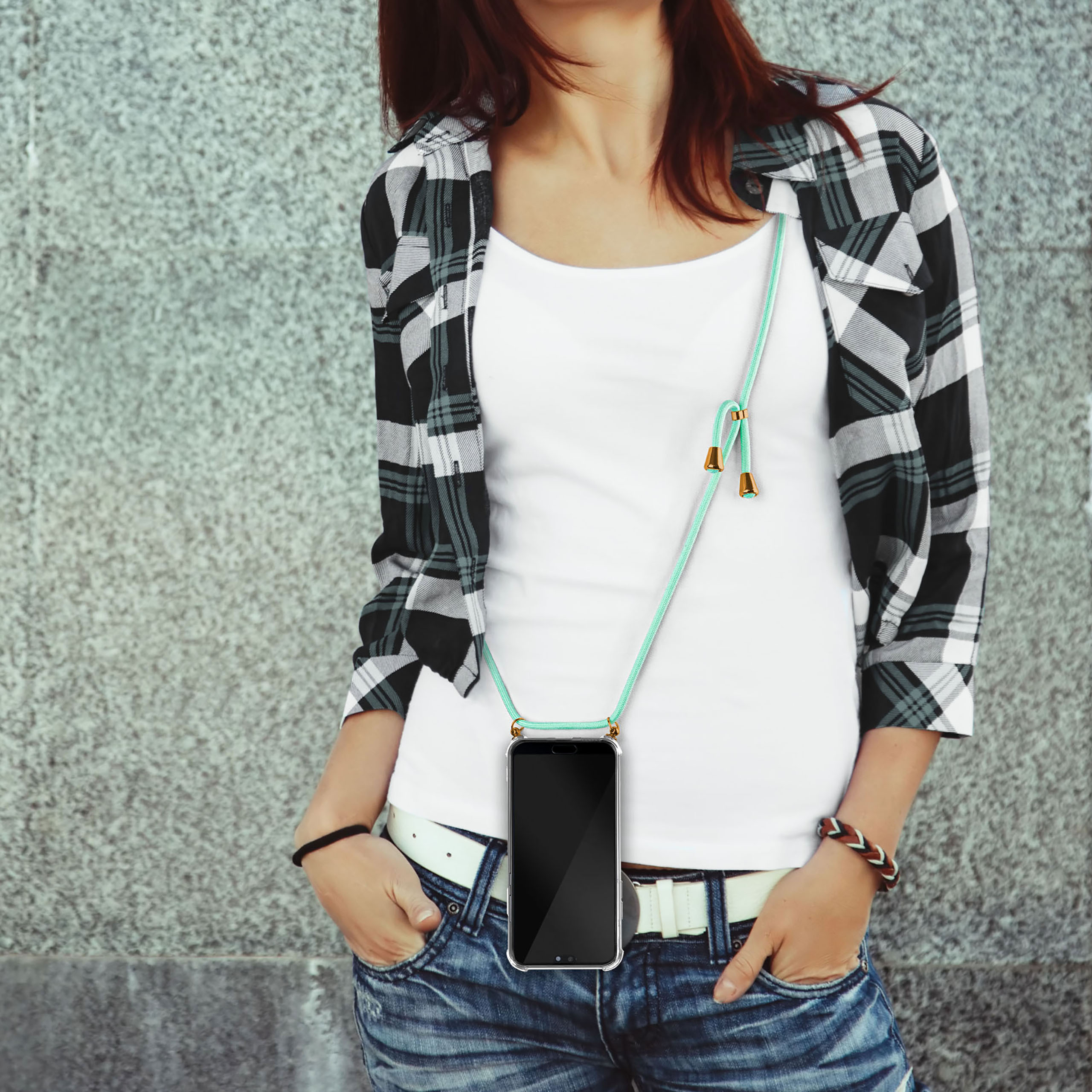 Eine Frau mit einer Handykette, Jeans und einem karierten Hemd.