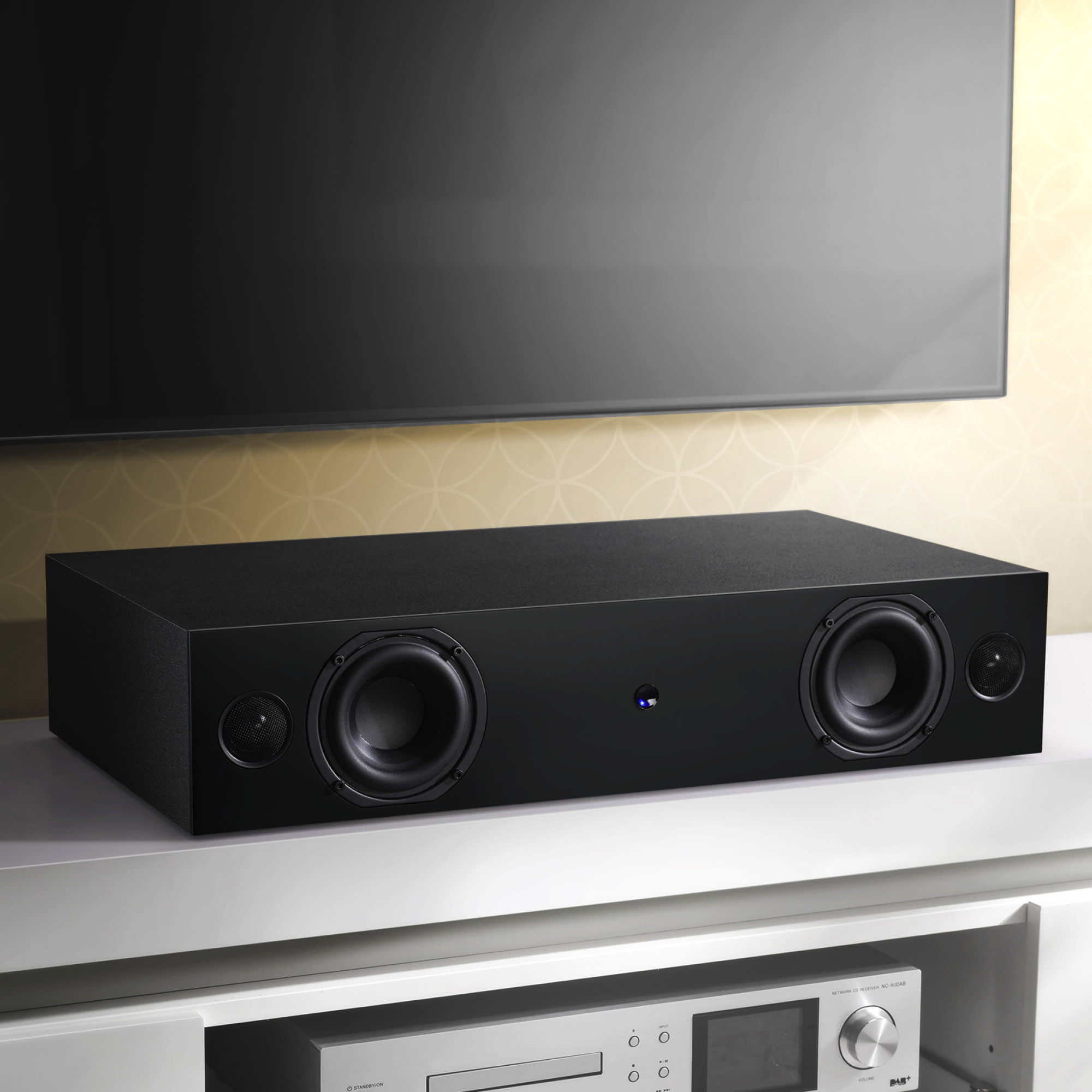 Schwarze Soundbar unter einem Fernseher. Die Soundbar hat zwei Lautsprecher und ein zentrales Display.