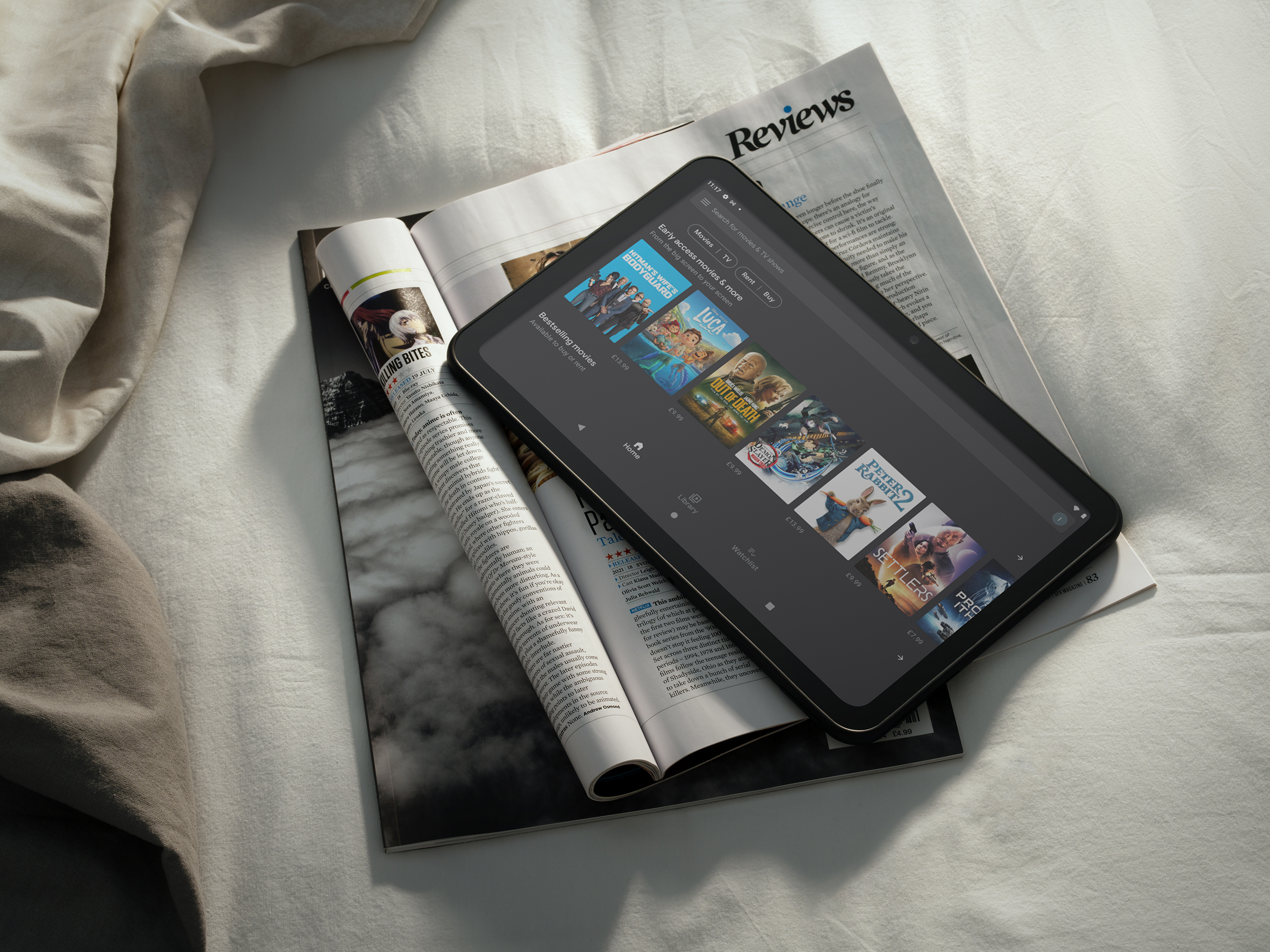 Ein Tablet auf offenen Zeitschriften. Das Tablet zeigt eine Film-App mit verschiedenen Filmcovern.