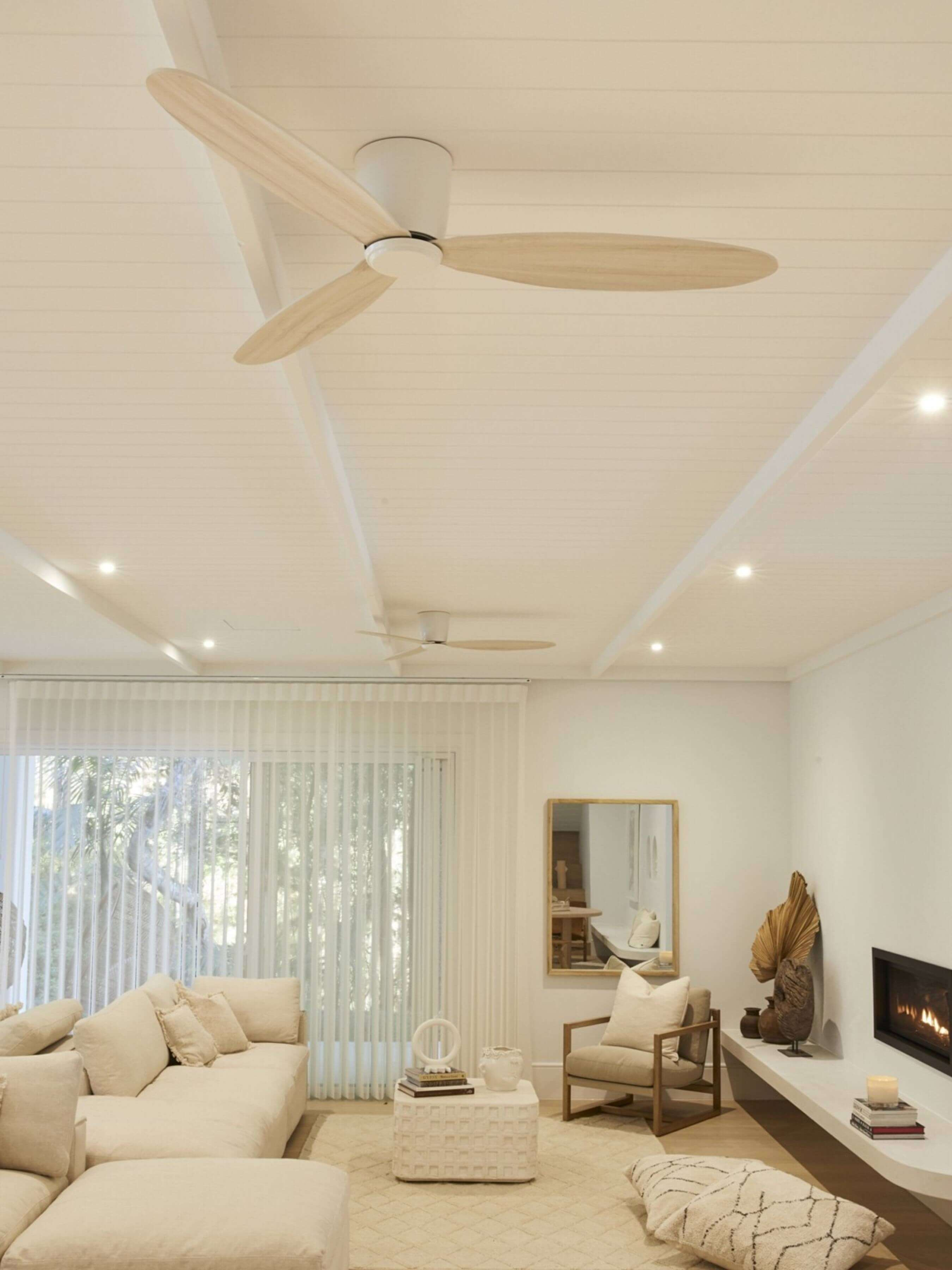 Weiße Decke mit zwei Ventilatoren mit Holzblättern. Wohnzimmer mit beigen Möbeln und Deko.