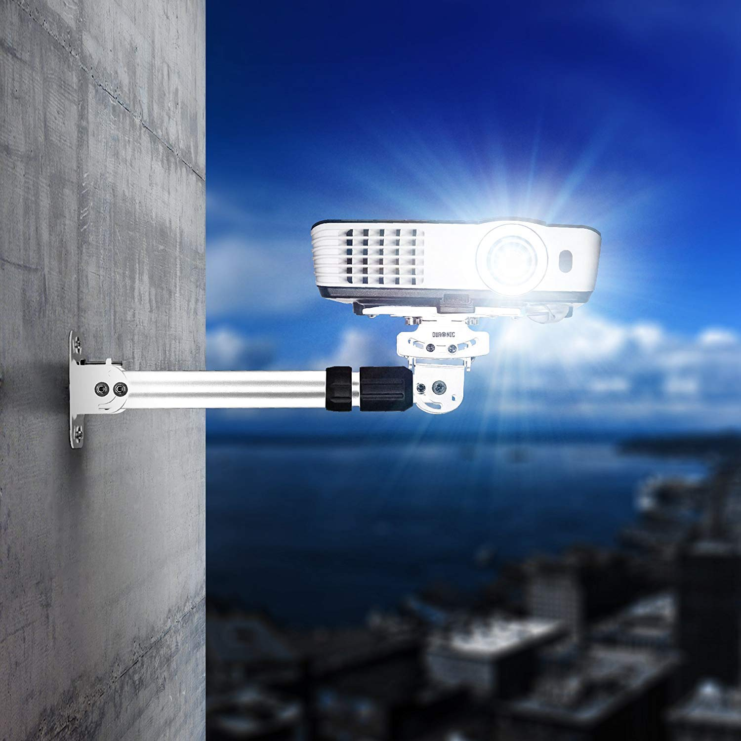 Proyector blanco montado en una pared. Cielo azul y mar en el fondo.