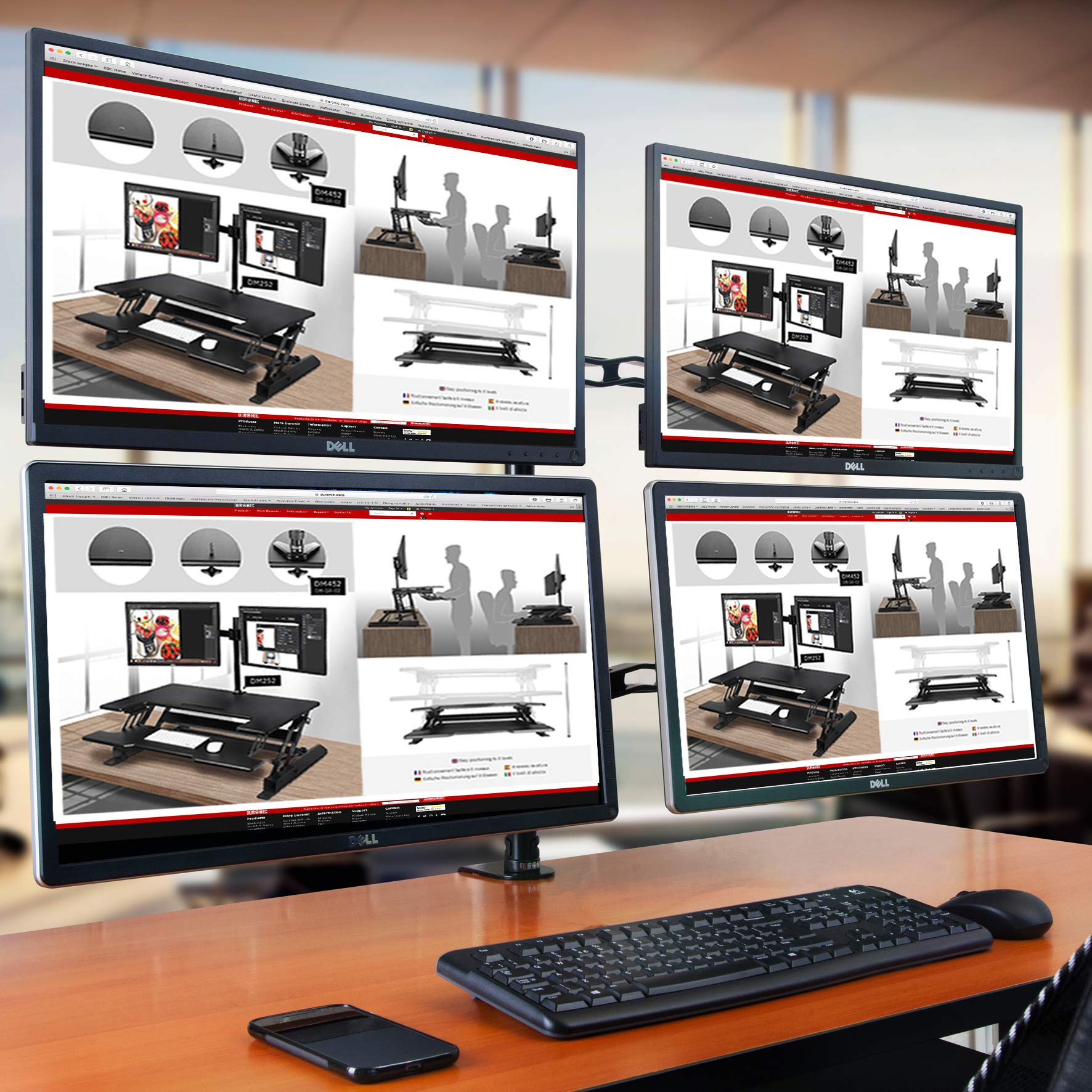 Vier Computerbildschirme zeigen das gleiche Webdesign. Ein Schreibtisch mit Tastatur, Maus und Telefon.