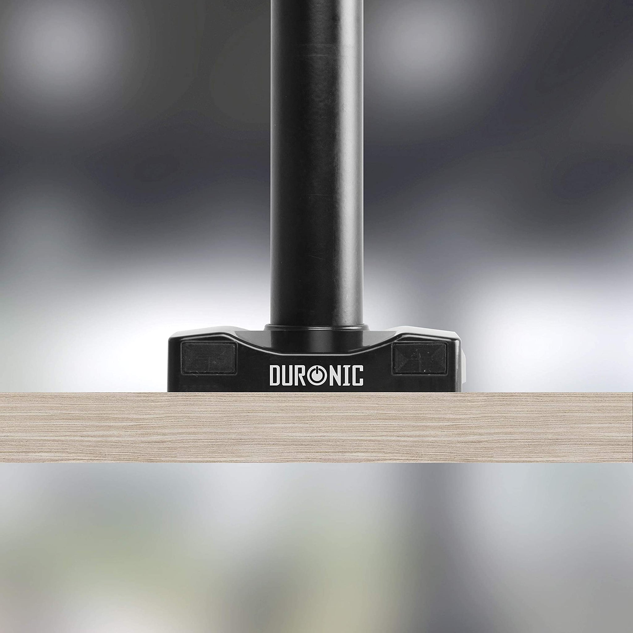 Brazo de monitor negro y metálico, marca DURONIC, montado en superficie de madera.