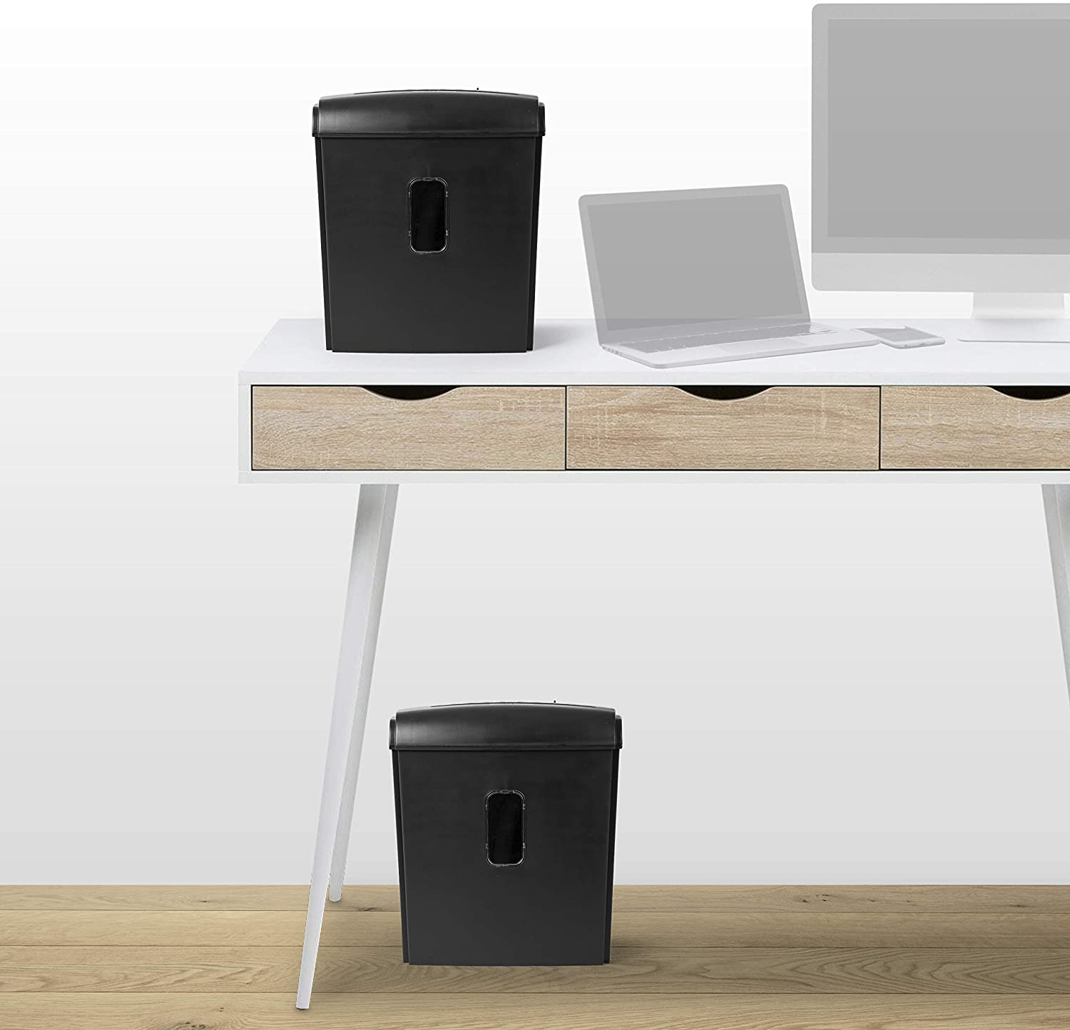 Zwei schwarze Aktenvernichter auf einem weißen Schreibtisch, mit Laptop im Hintergrund.