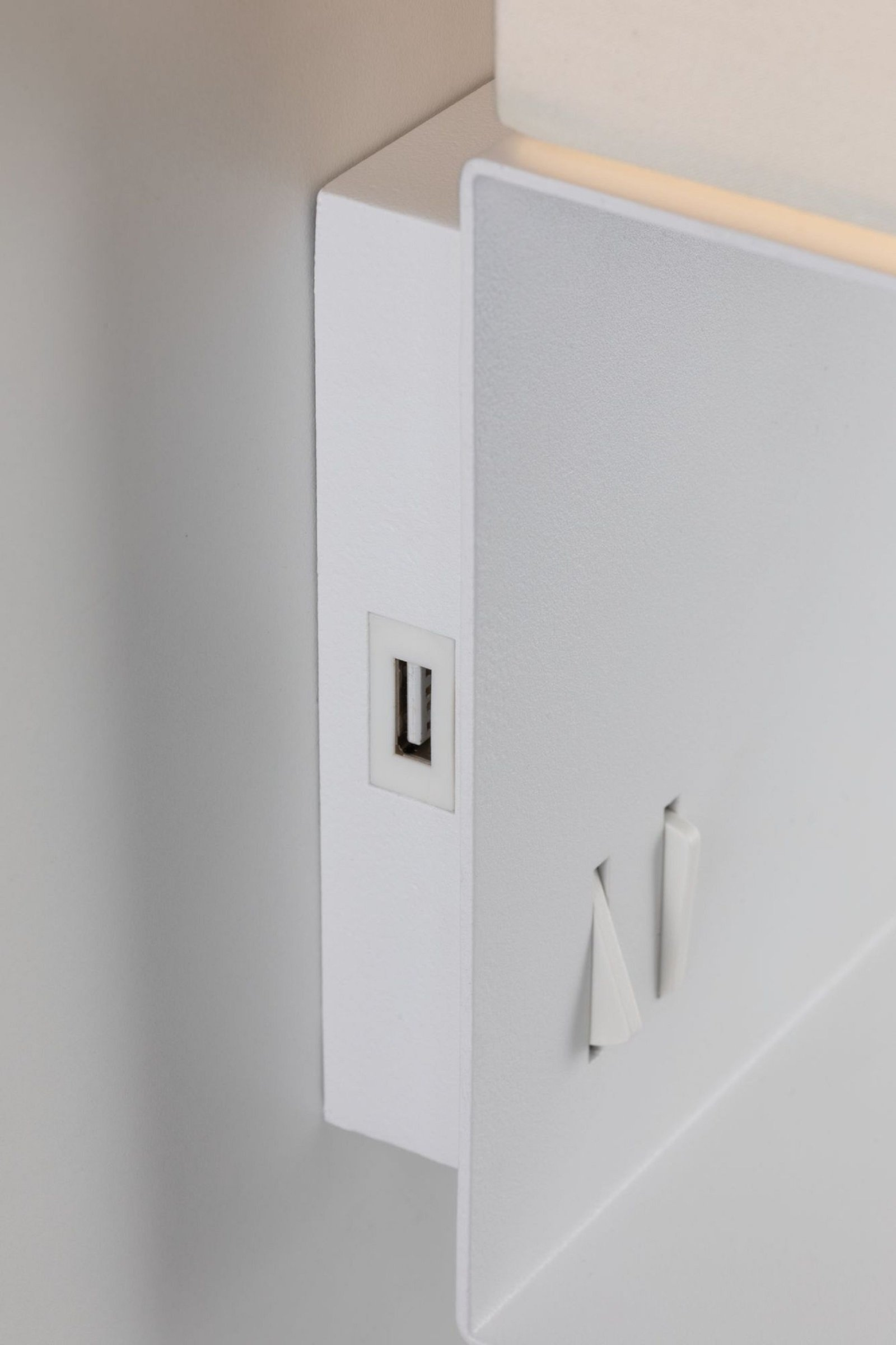 Eine weiße Wandhalterung mit USB-Anschluss, Schalter und Licht. Nahaufnahme.