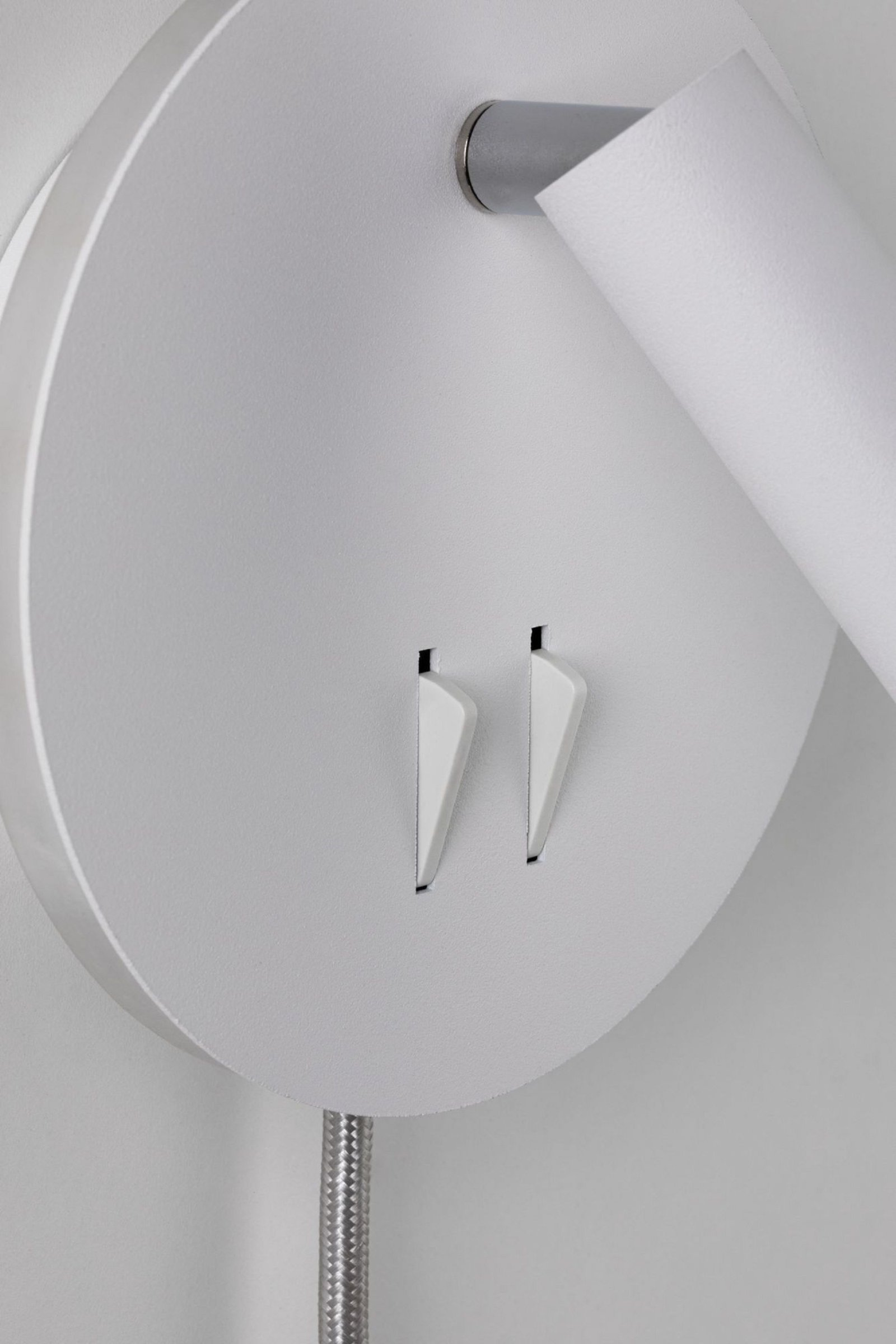 Weiße kreisförmige Wandleuchte mit silbernen Details. Sie hat zwei Schlitze und ein Metallkabel.