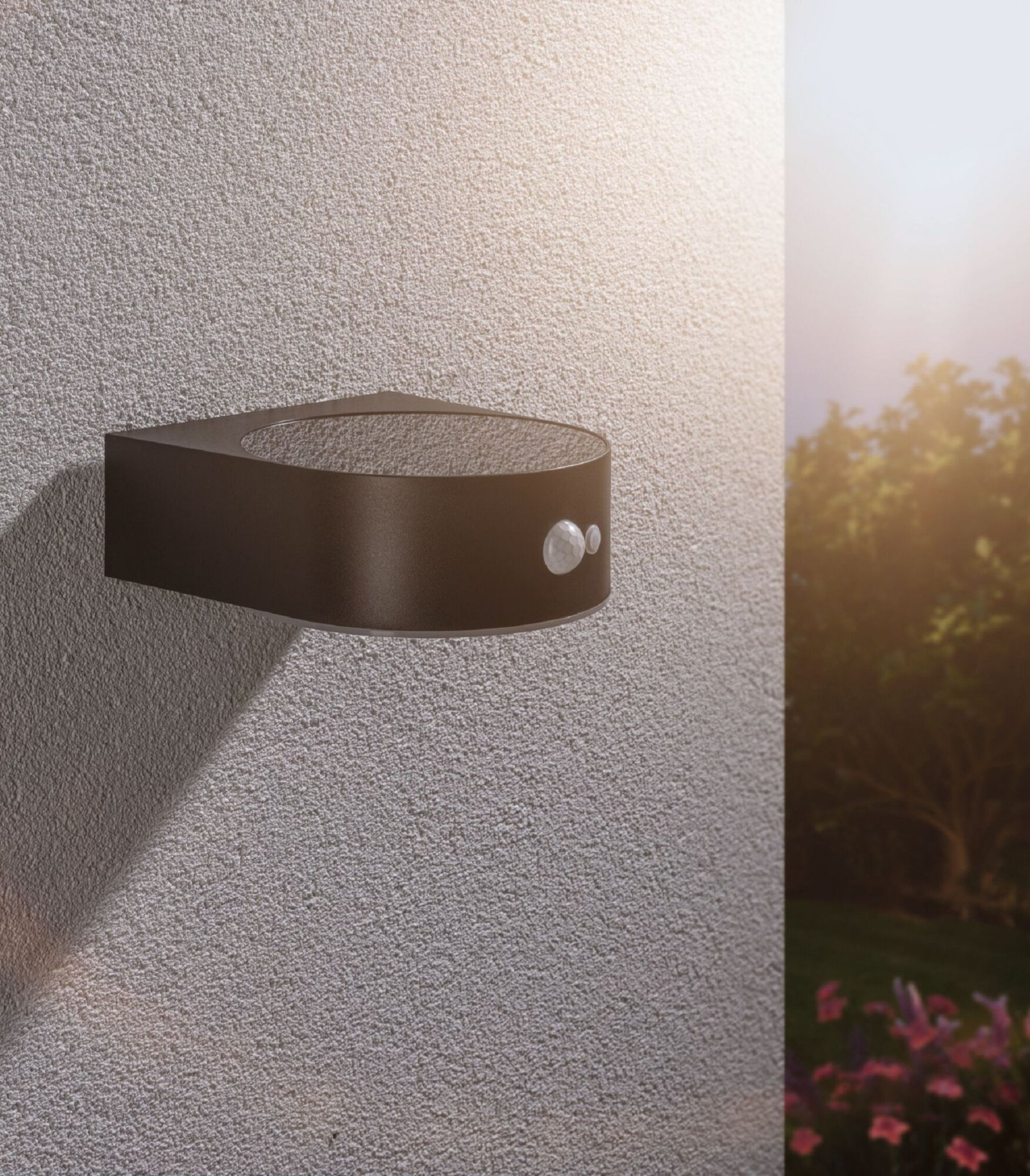 Zewnętrzna lampa ścienna na teksturowanej ścianie. Lampa jest ciemnobrązowa.