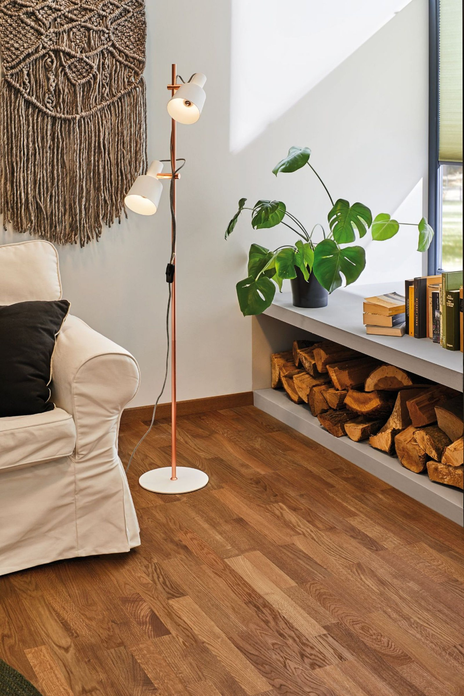 Wnętrze pokoju z lampą podłogową z dwoma światłami i białą sofą. Drewniana podłoga.