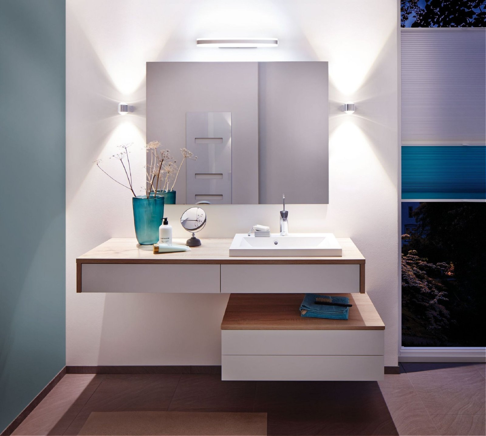 Modernes Badezimmer mit schwebendem Waschtisch, Spiegel und Wandleuchten.
