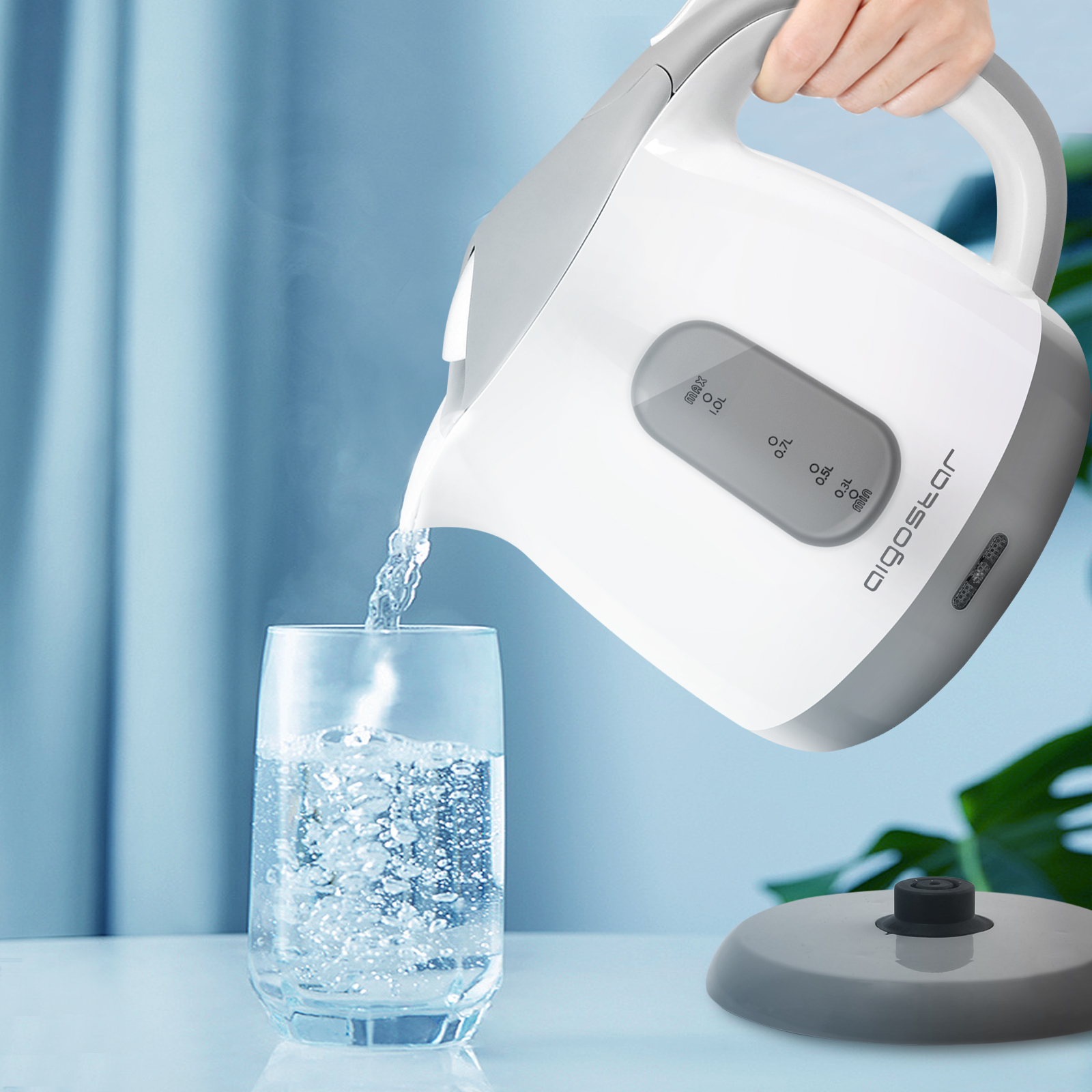 Ein weiß-grauer Wasserkocher gießt Wasser in ein Glas.