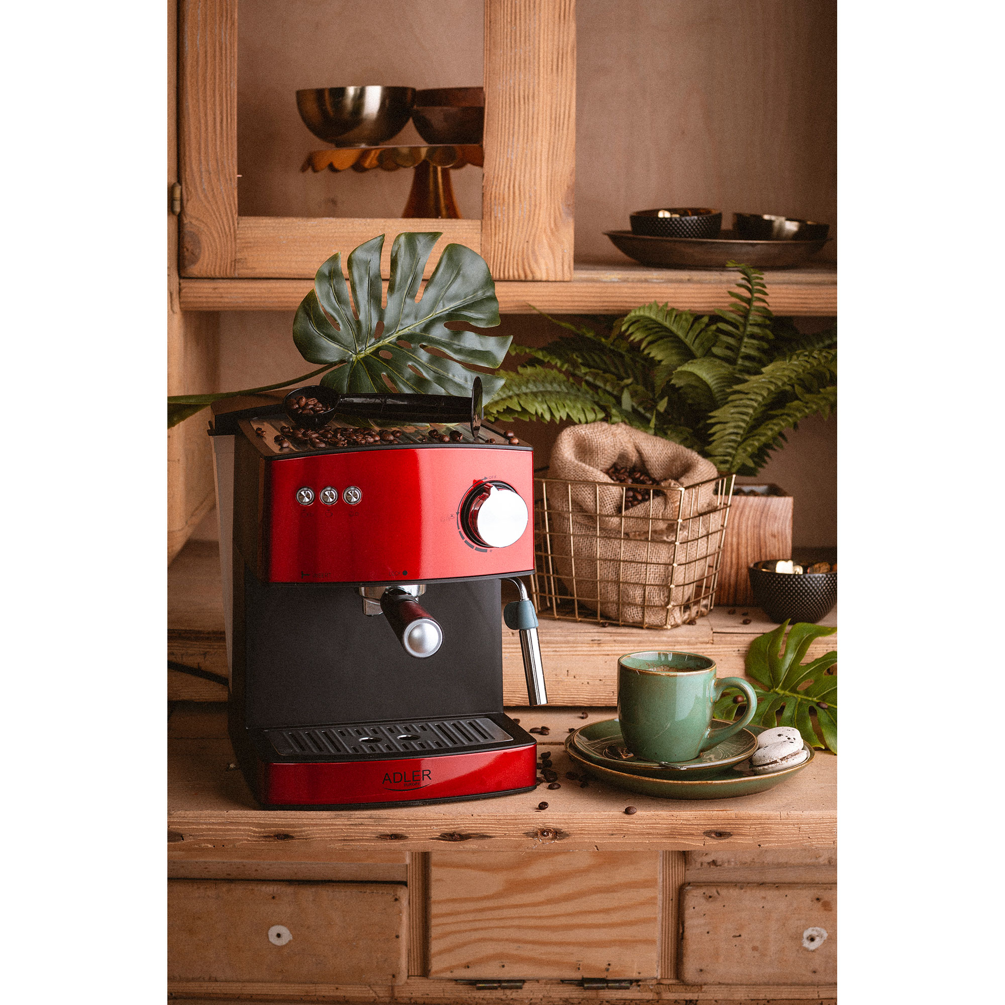 Rote und schwarze Espressomaschine mit Kaffeebohnen, Tasse und Dekoration.