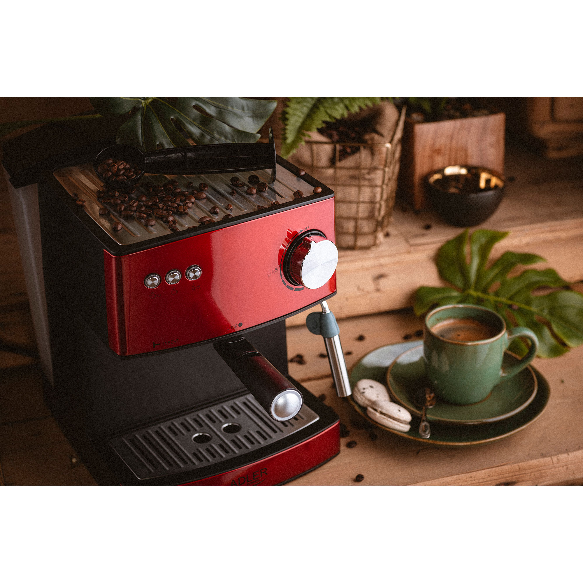 Rote und schwarze Espressomaschine mit Kaffeebohnen, Tasse und Blatt auf Holztisch.