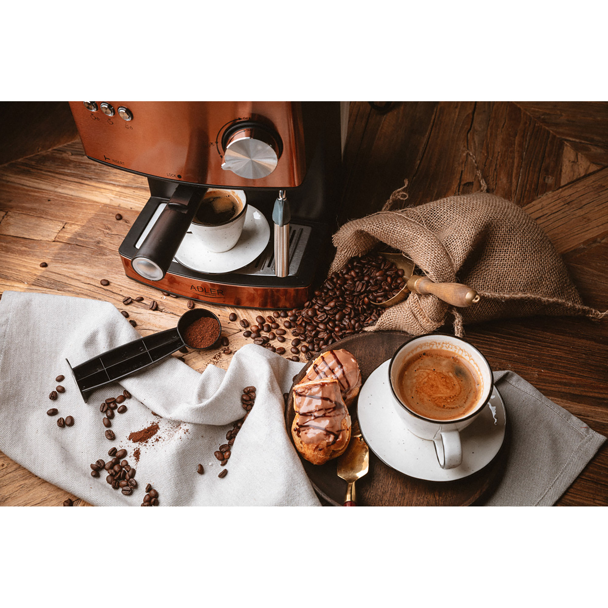 Una macchina da caffè con caffè, chicchi e pasticcini su un tavolo di legno.