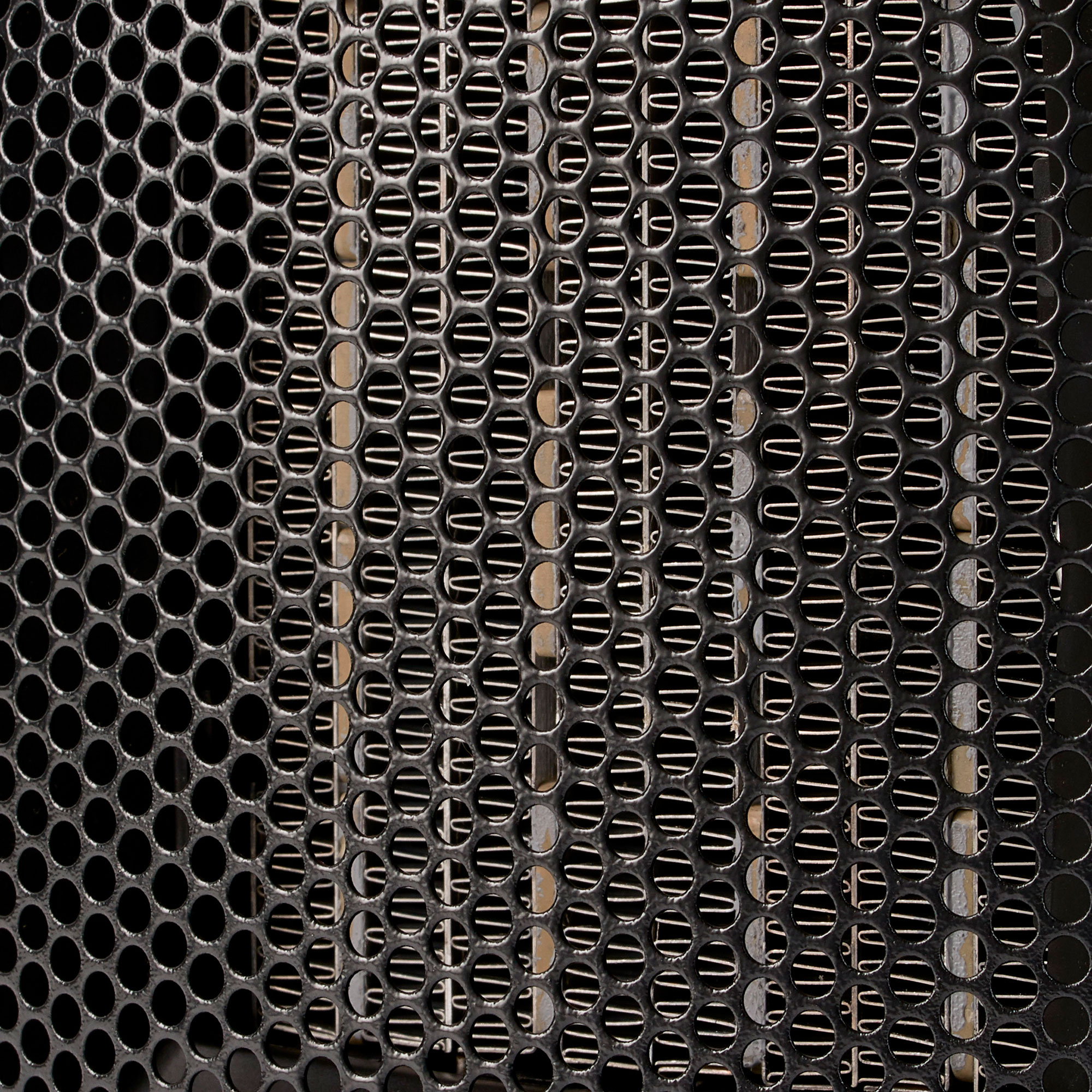 Zbliżenie czarnego metalowego grilla z wieloma małymi otworami.