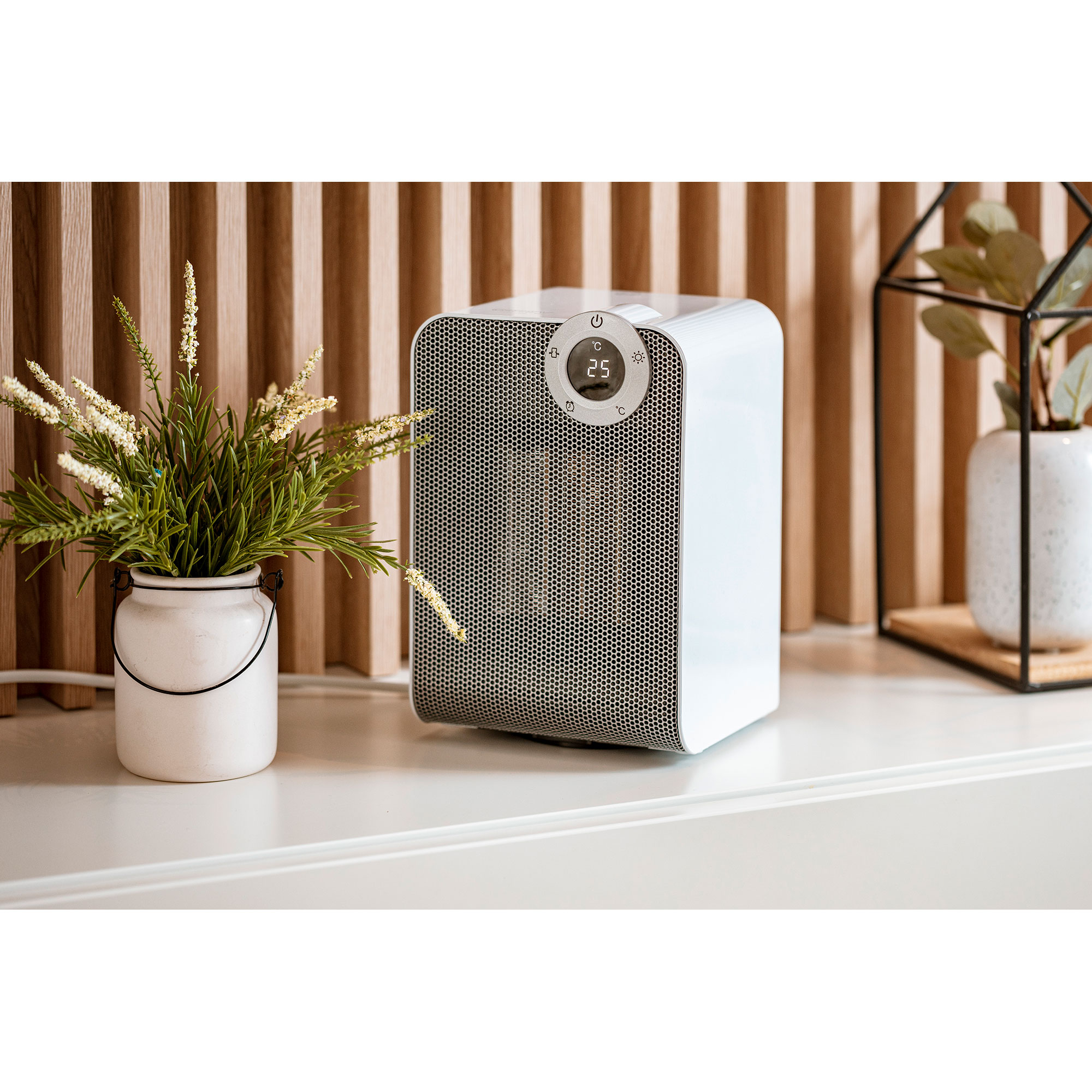 Weißer Elektroheizer mit Digitalanzeige, neben einer Blumenvase.