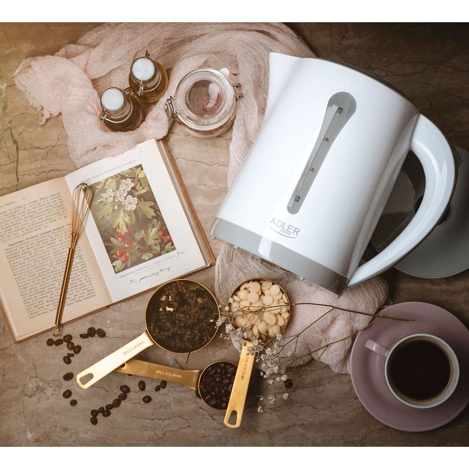 Scena kuchenna. Biały czajnik elektryczny, miarki, otwarta książka i ziarna kawy na stole.