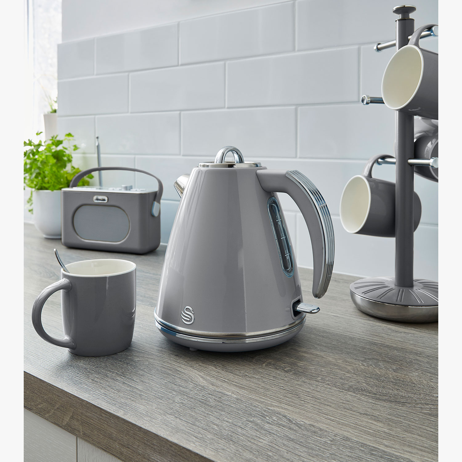 Grijze Swan waterkoker en accessoires op een houten oppervlak, met een witte achtergrond.