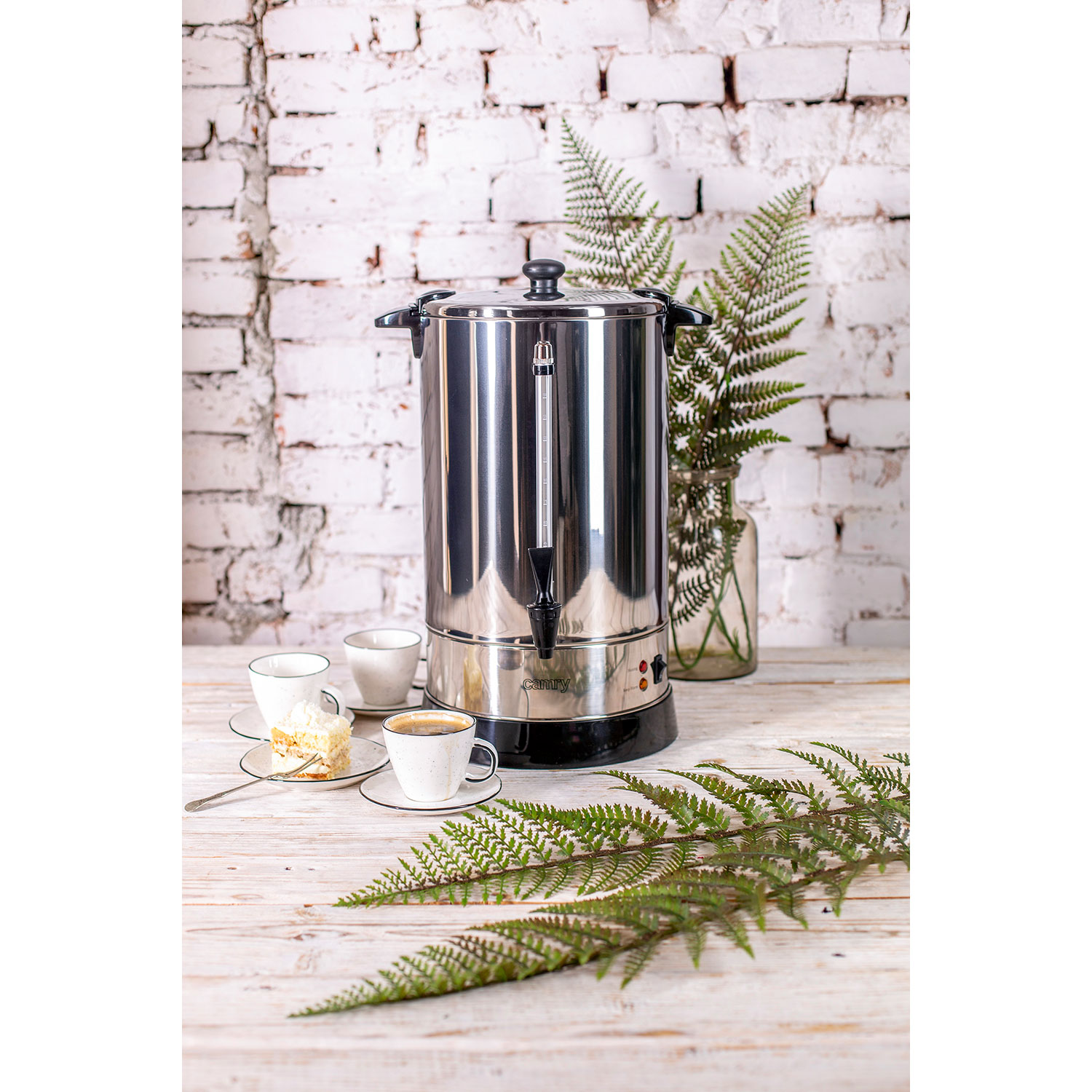 Stalowy ekspres do kawy i filiżanki z ciastem na drewnianym stole.