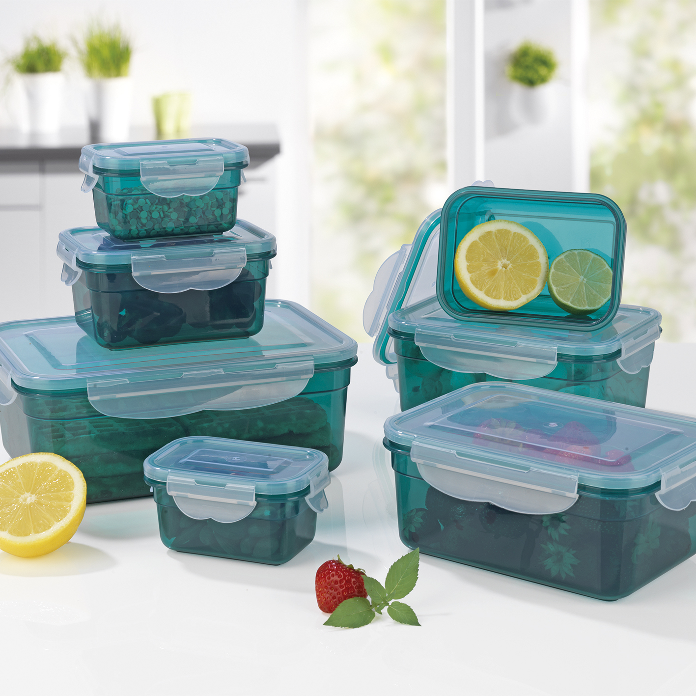 Lebensmittelbehälter, mit teal-farbenem Kunststoff und klaren Deckeln. Enthält Zitronen, Limetten und Erdbeeren.