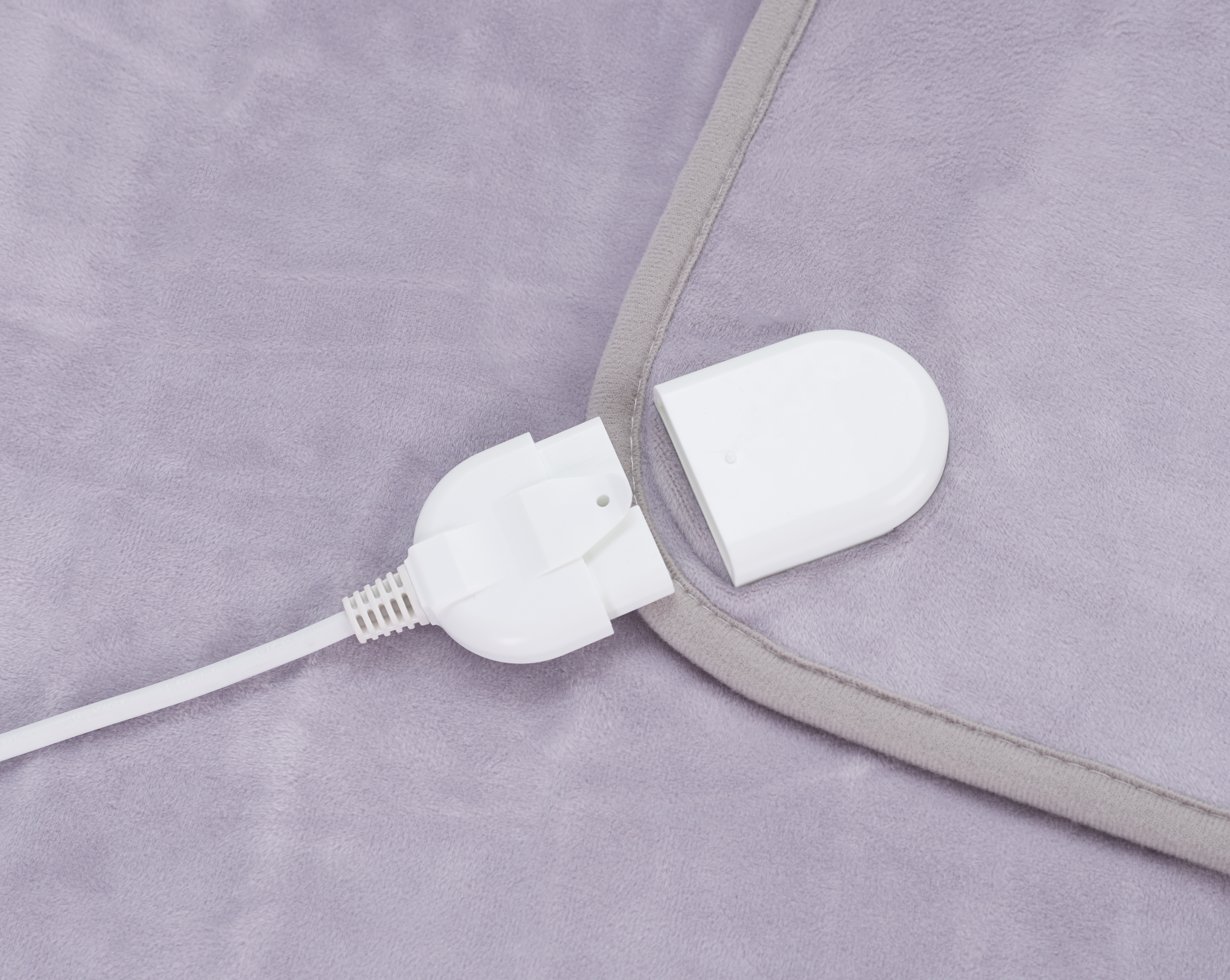 Szara poduszka grzewcza z białym złączem elektrycznym.