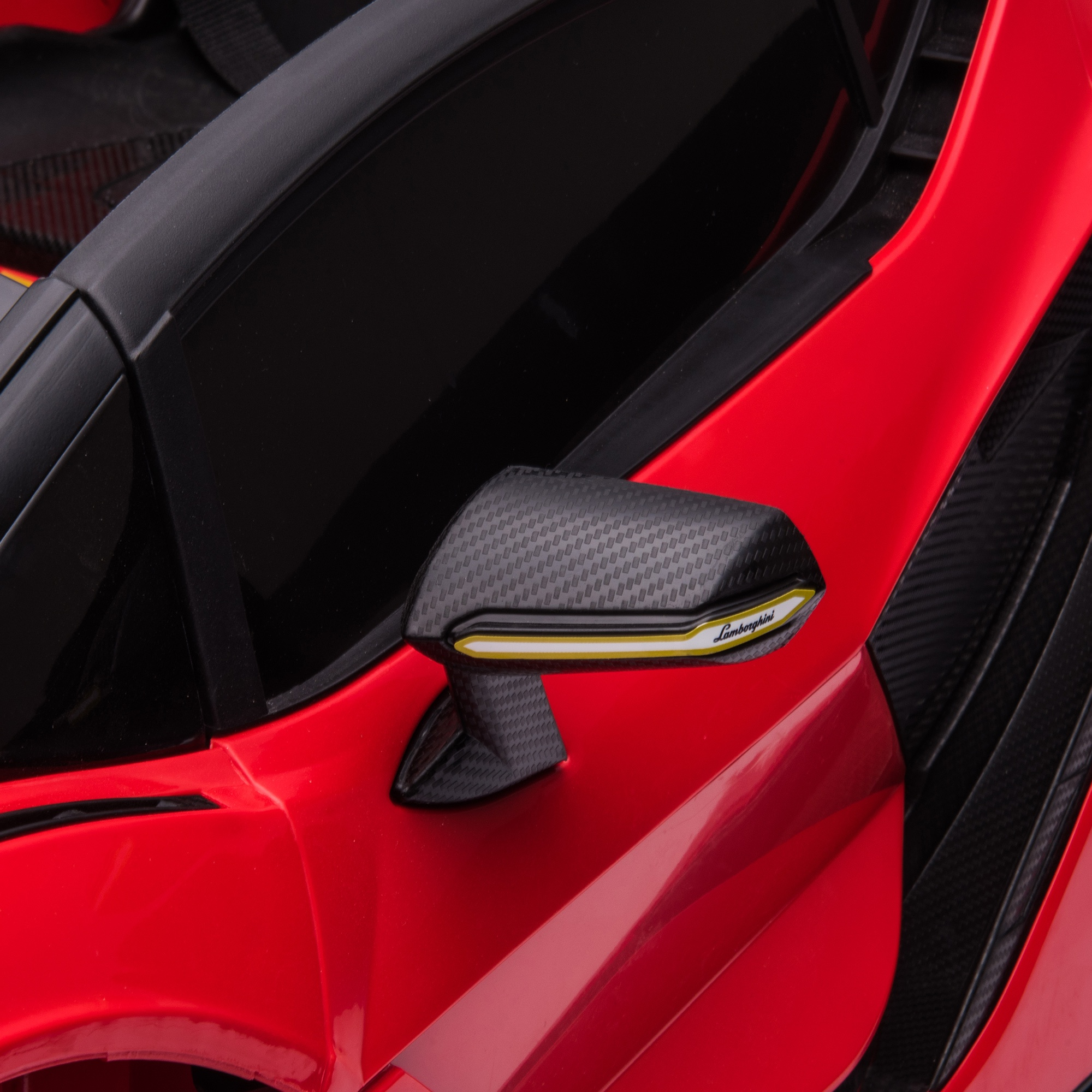 Espejo retrovisor lateral de coche rojo, mostrando textura de fibra de carbono y un acento amarillo.