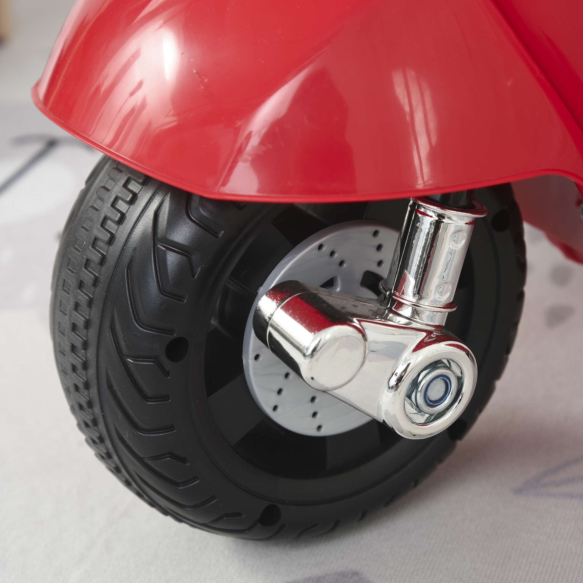 Ruota di scooter giocattolo rossa, pneumatico nero, dettagli cromati.