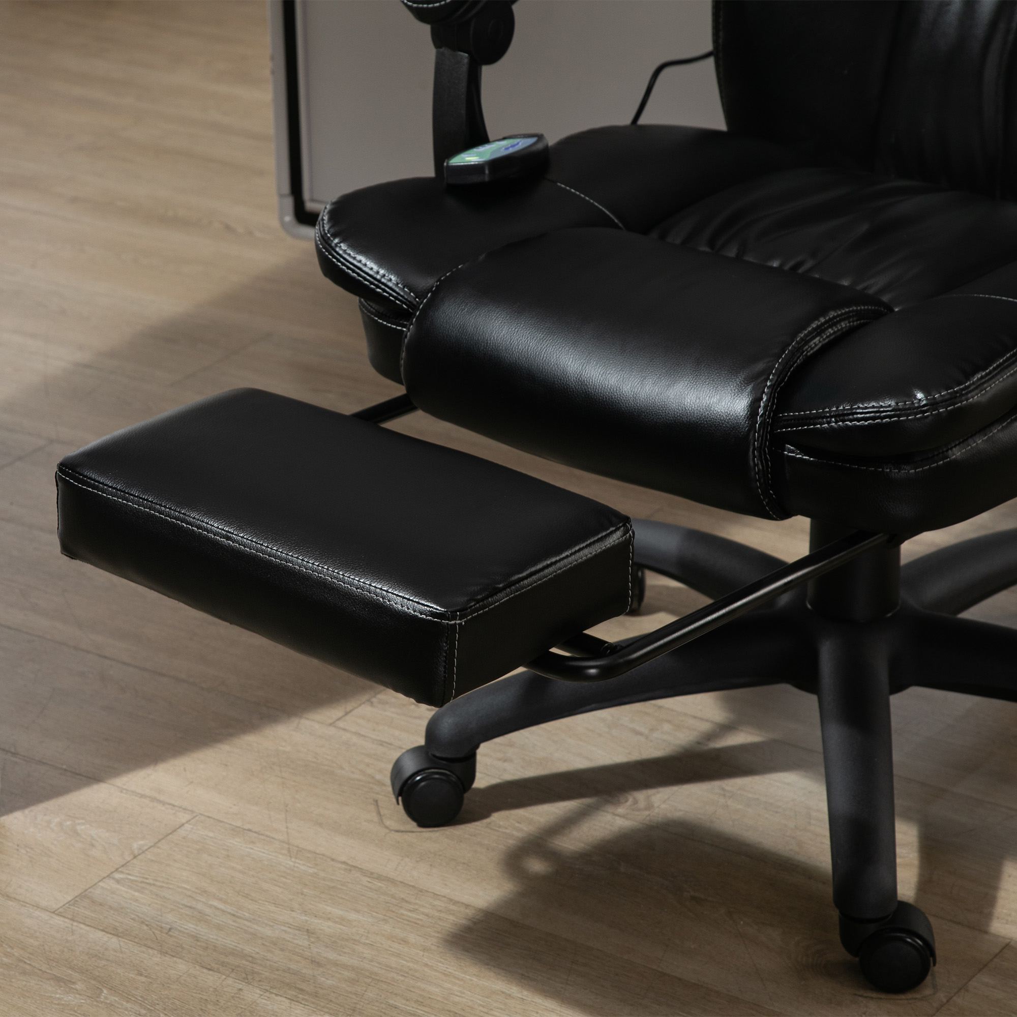Una sedia da ufficio nera con poggiapiedi, su un pavimento in legno chiaro.