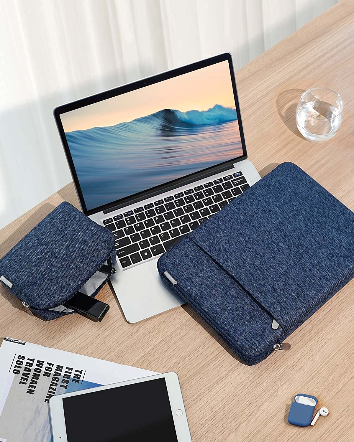 Ein Laptop, ein Tablet und eine Hülle auf einem Holztisch, mit anderem Zubehör.