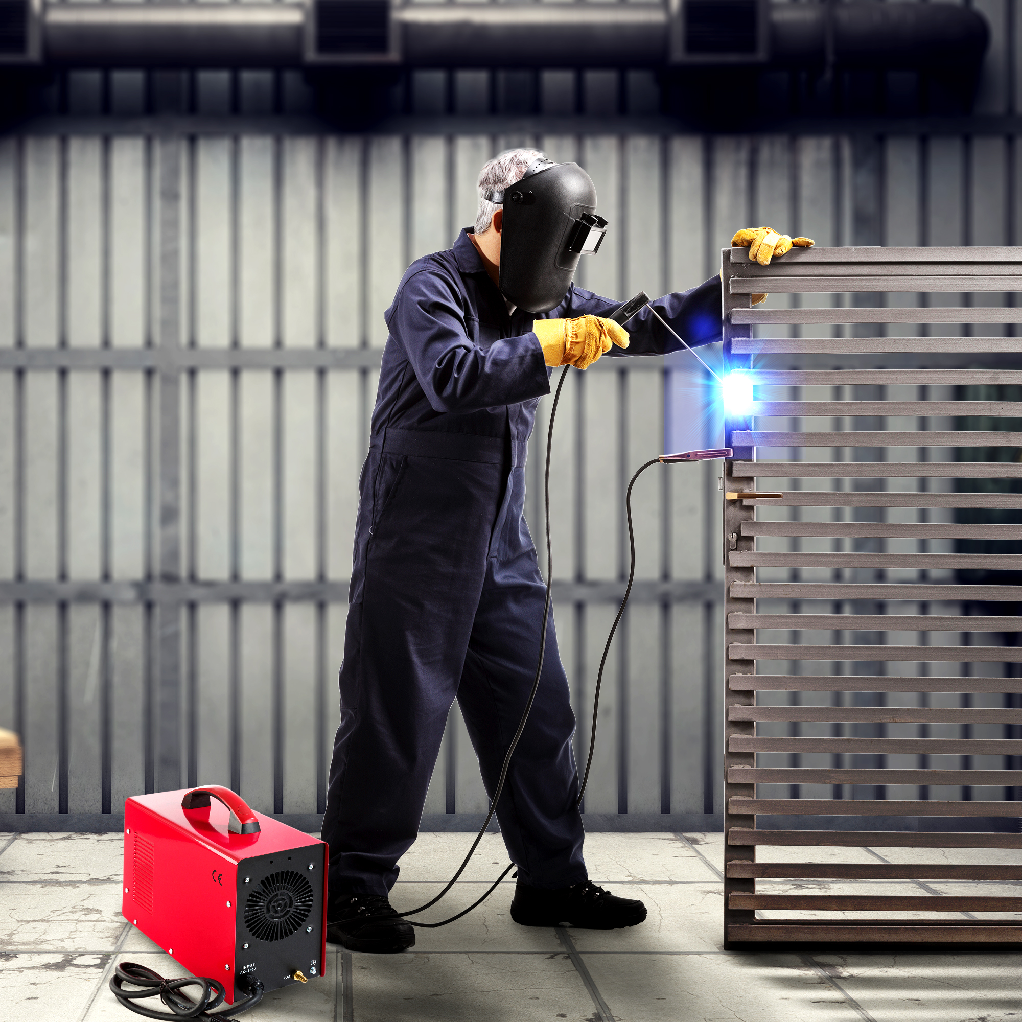 Schweißer, der ein Metalltor schweißt. Eine rote Schweißmaschine steht am Boden. Industrieller Hintergrund.
