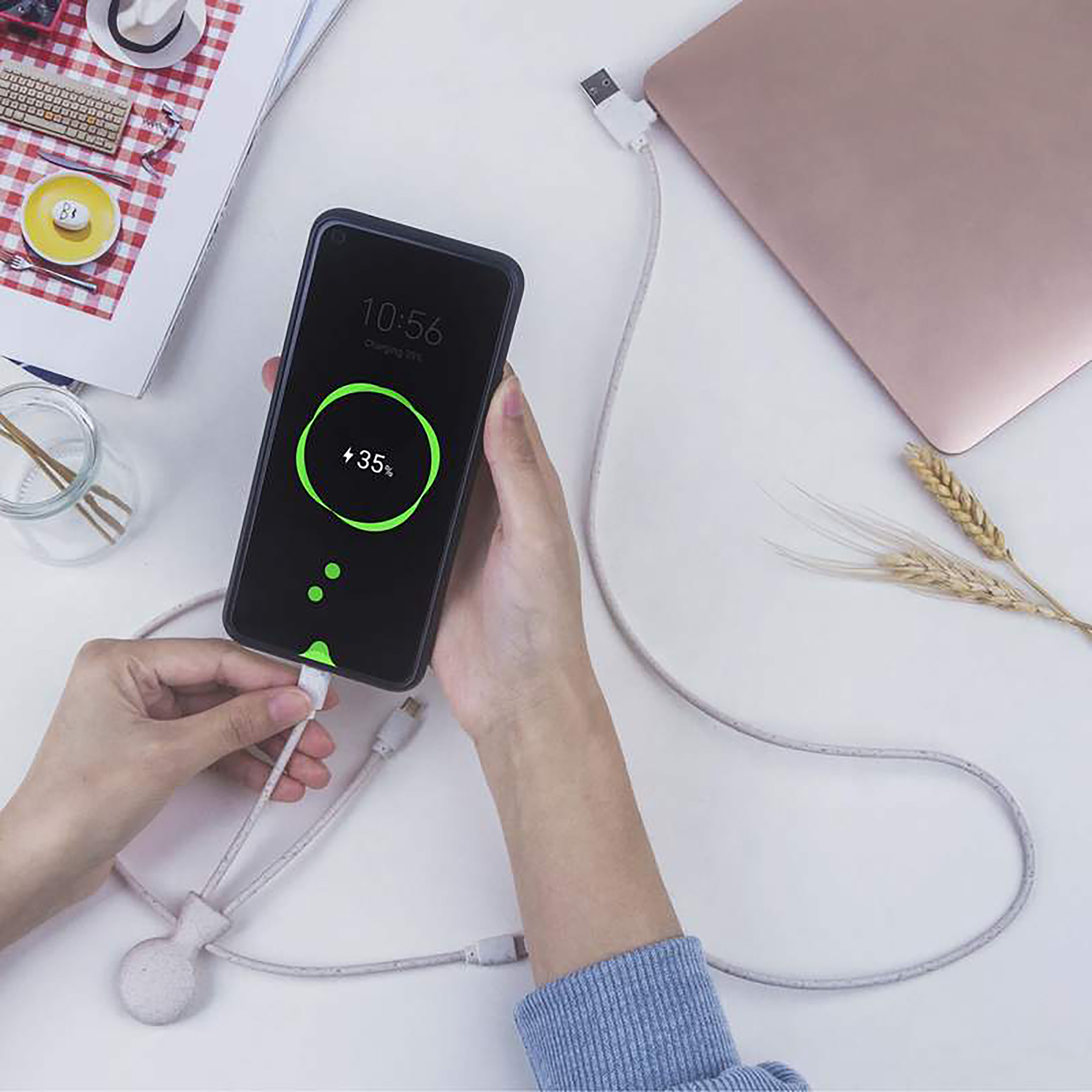 Una persona tiene un telefono che si sta caricando. Lo schermo dice 'Charging 35%'.