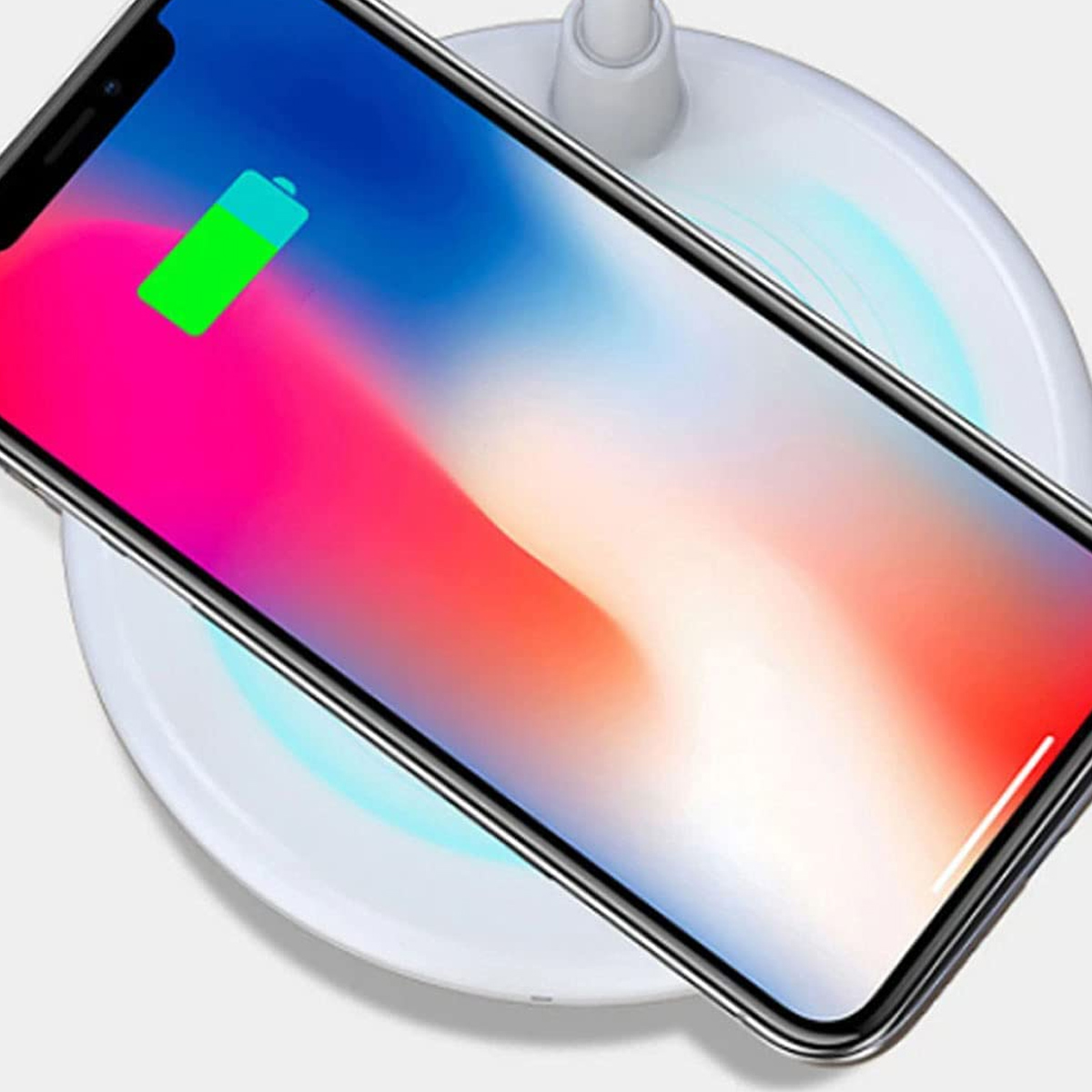 Smartphone cargándose en un cargador inalámbrico blanco, con un indicador de batería verde.