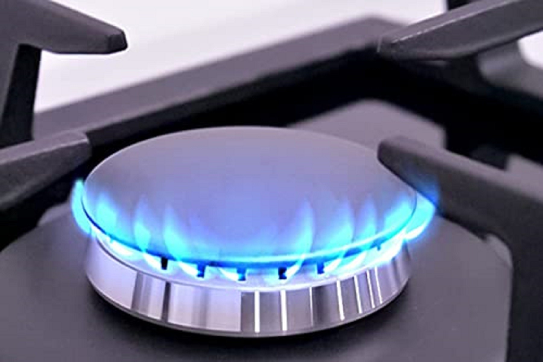 Primer plano de un quemador de cocina de gas con una llama azul. Encimera negra con quemador.