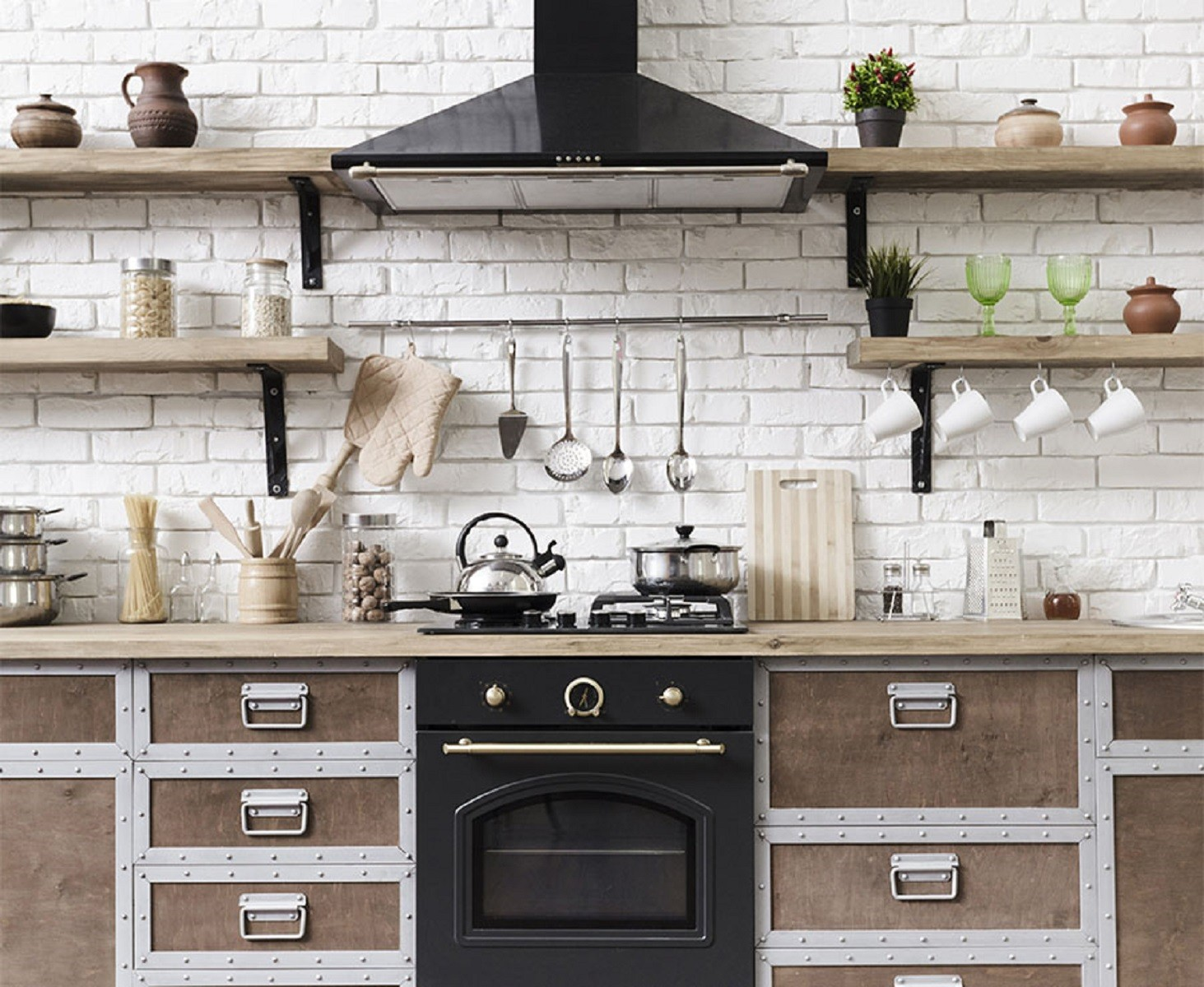 Cocina con estantes de madera, utensilios y un horno negro. Interior luminoso y limpio.
