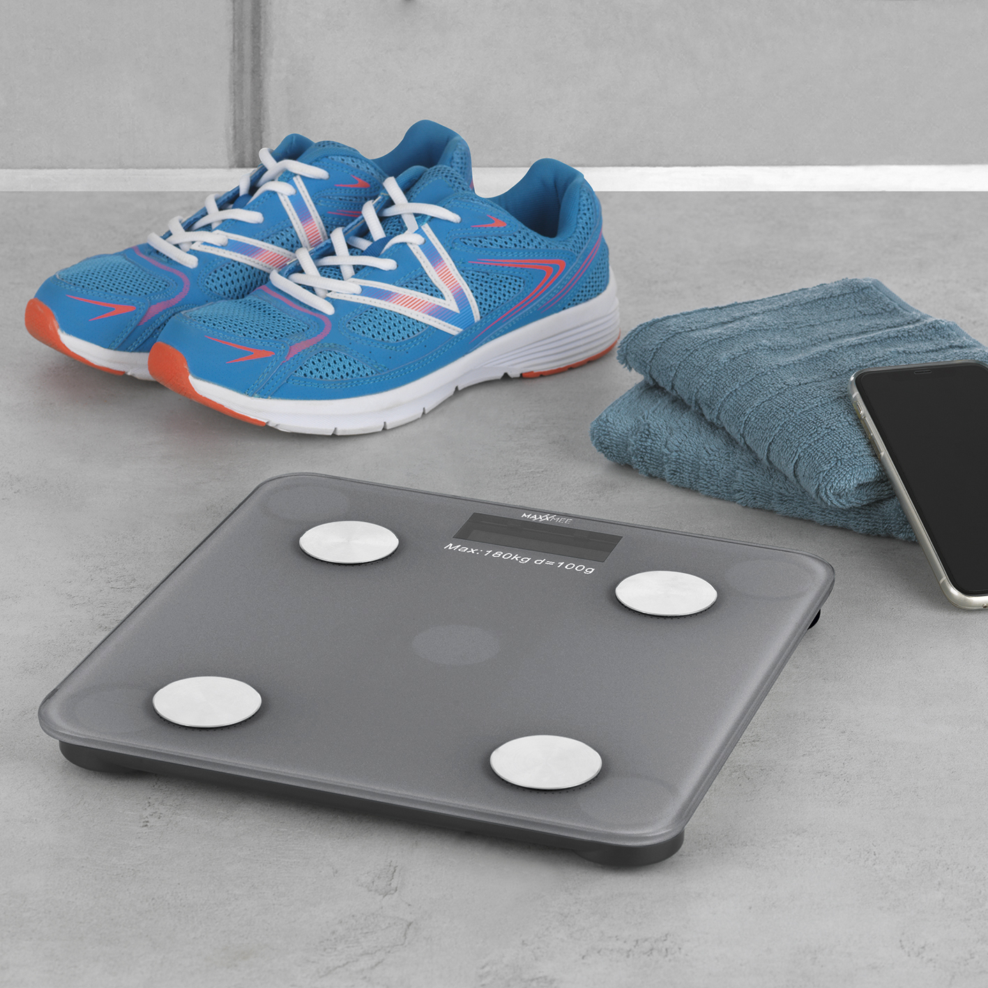 Digitale Waage mit Schuhen, Handtuch und Telefon. Zeigt Gewicht in kg an.