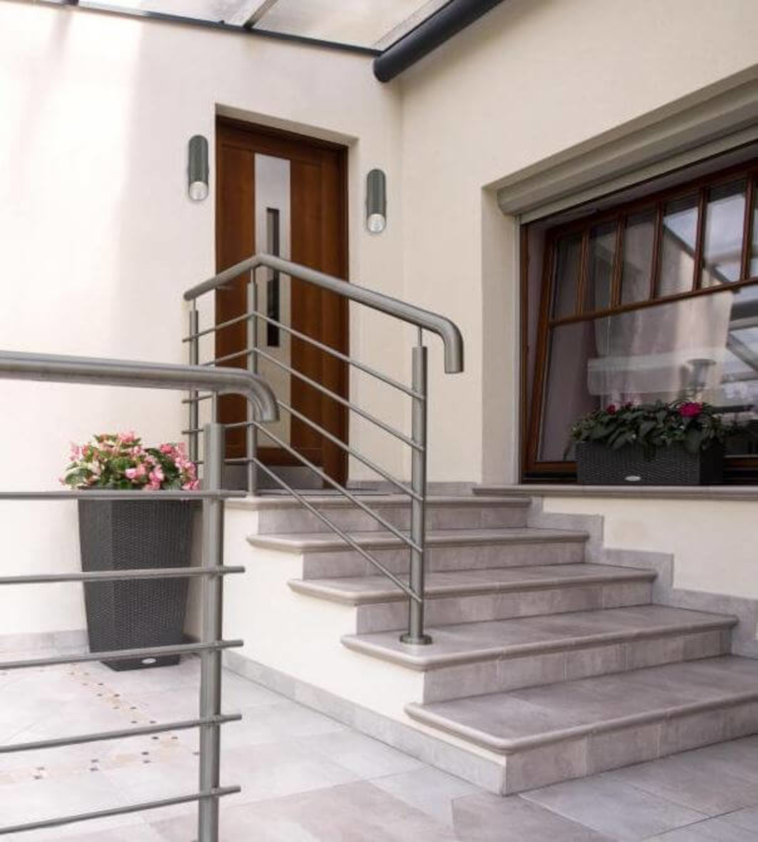 Eine Außentreppe mit Handlauf. Die Treppe führt zu einer Holztür.