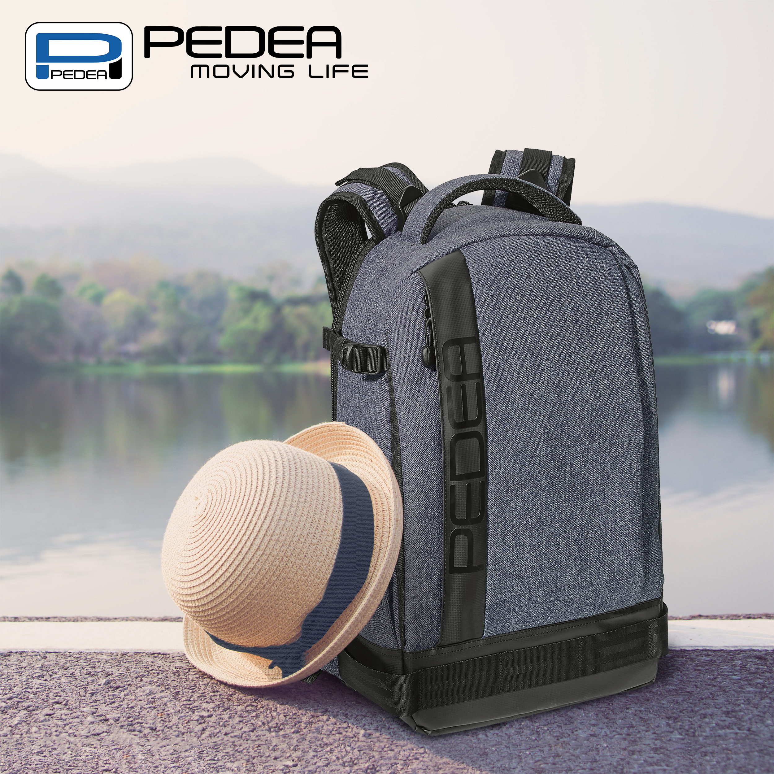 Ein grauer Rucksack und ein Strohhut mit blauem Band liegen auf einer gepflasterten Fläche mit See und Bergen.